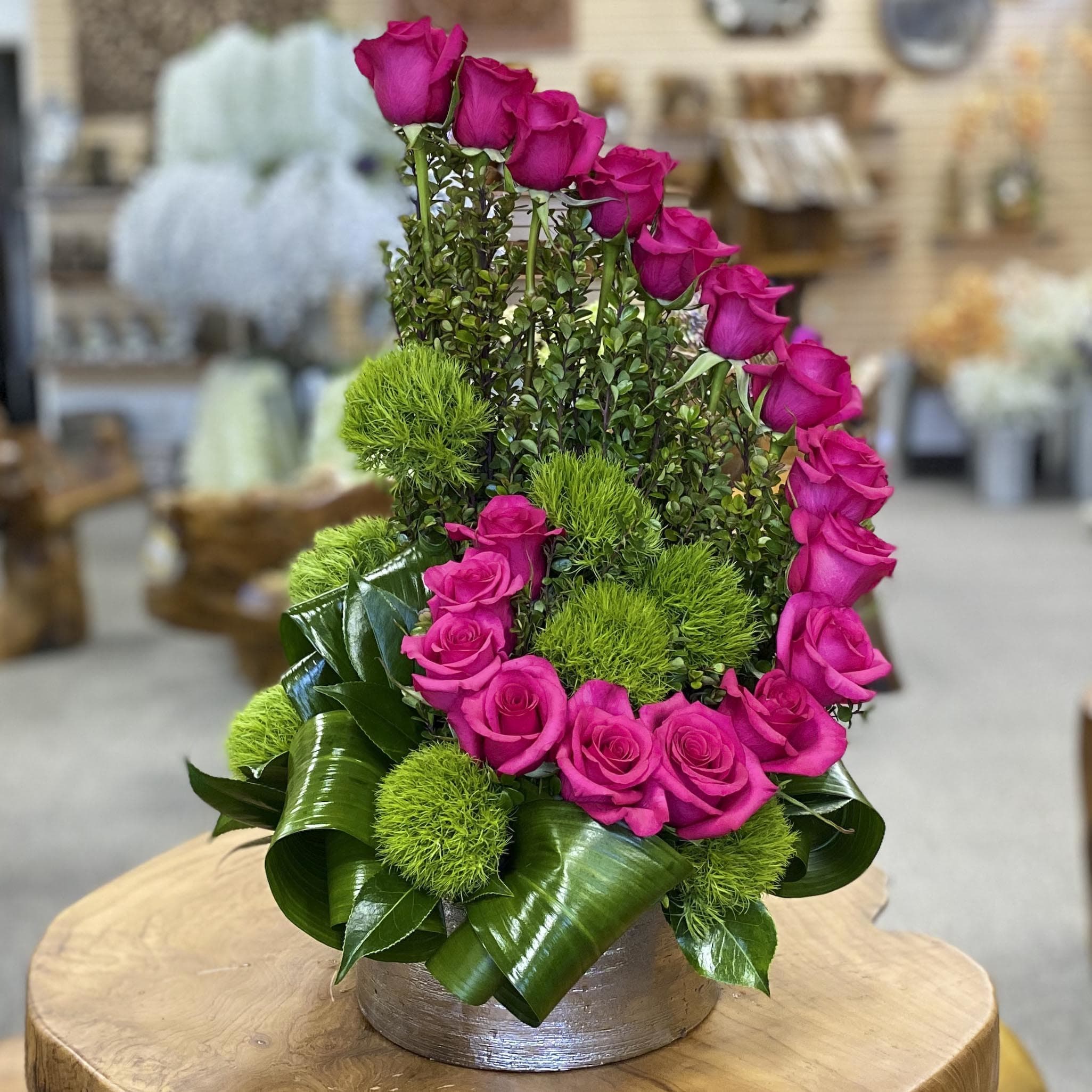 Pink roses arranged with green pom-pom accents in a low round container
