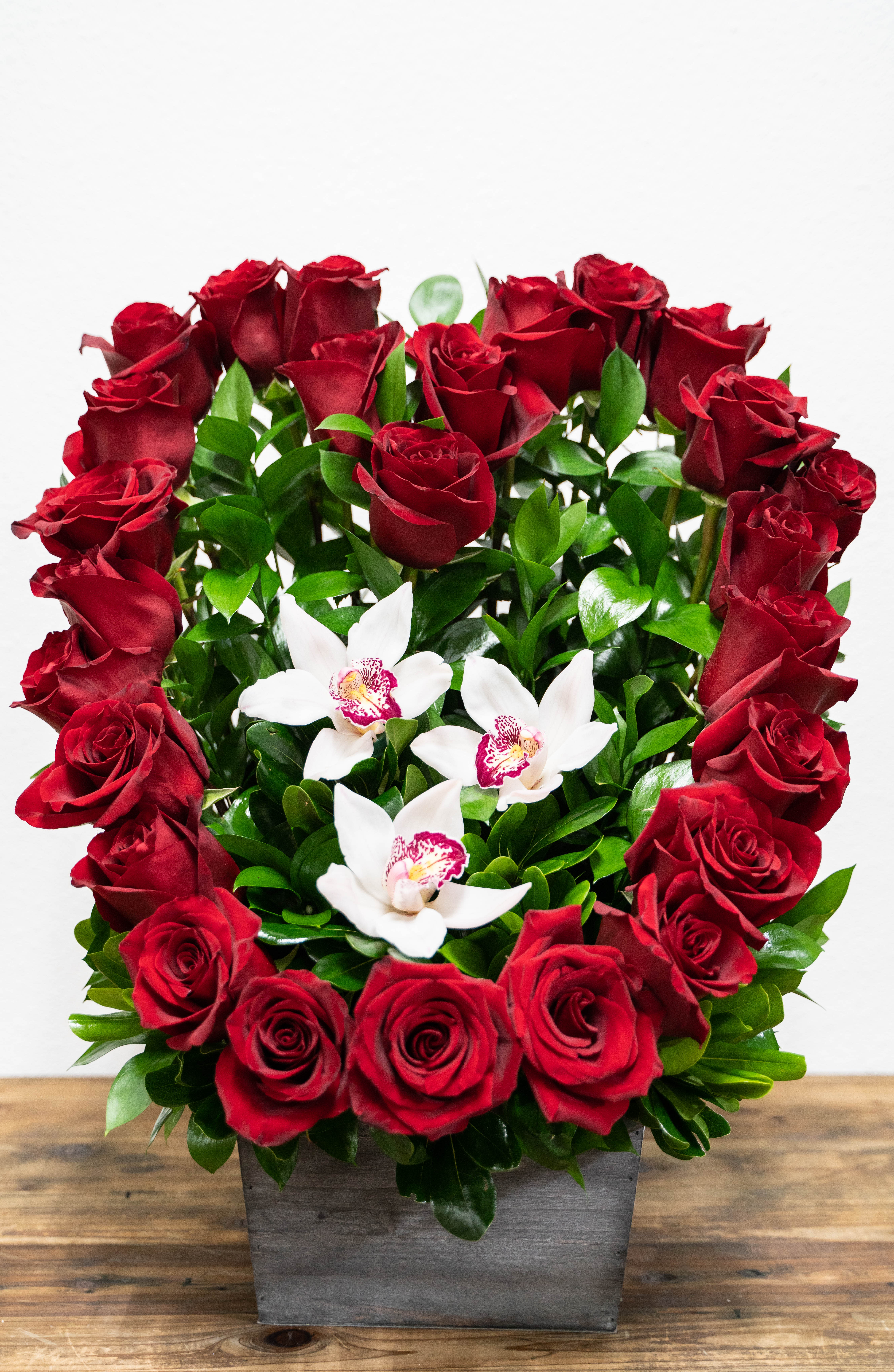 Red roses and white orchids in a square gray container
