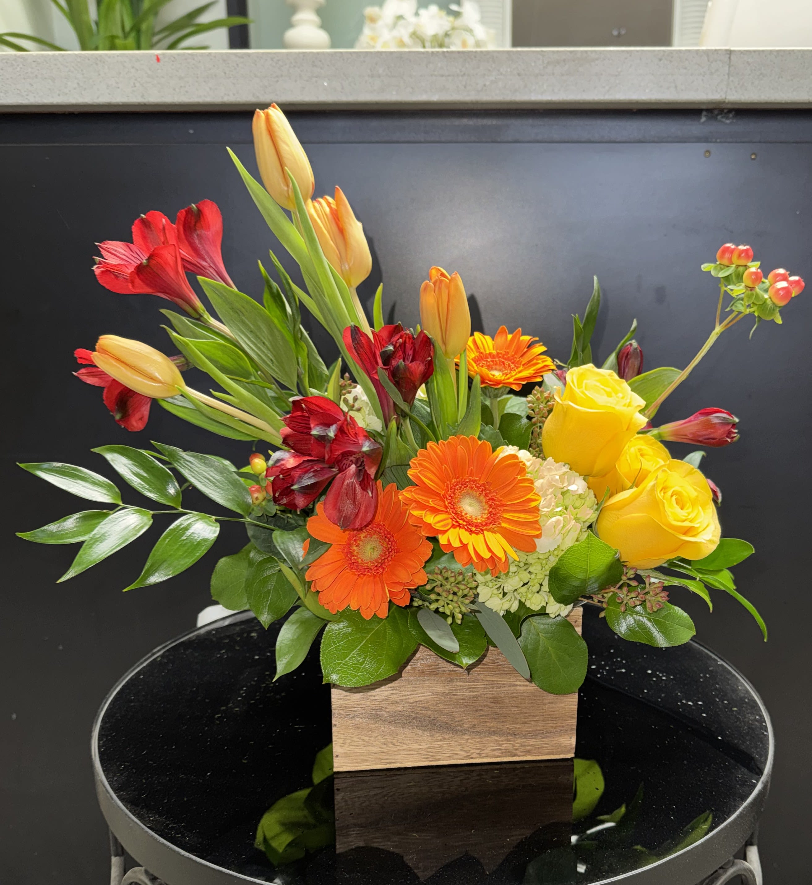 Mixed bouquet with yellow roses, gerbera daisies, and red-orange tulips in a wooden box