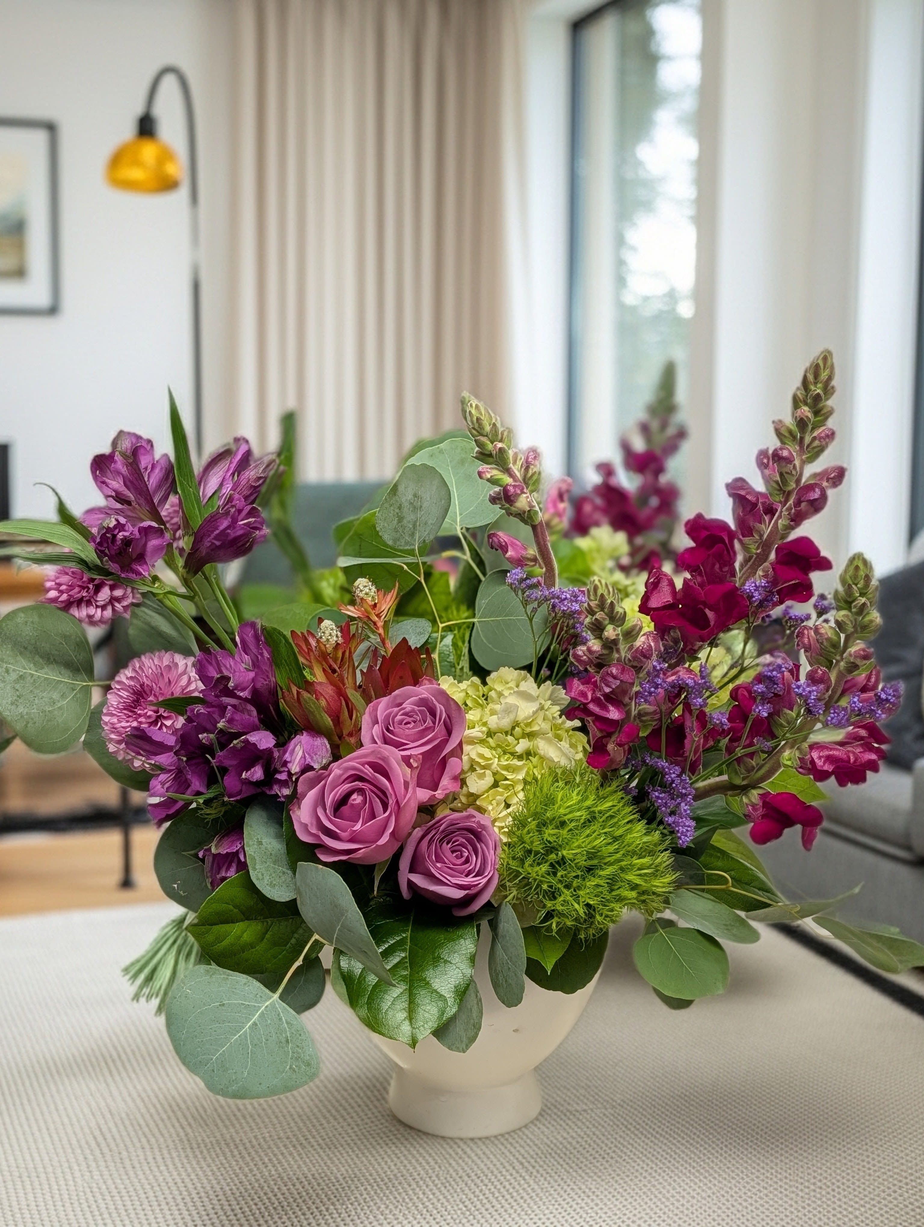 Purple and pink floral arrangement in a white vase
