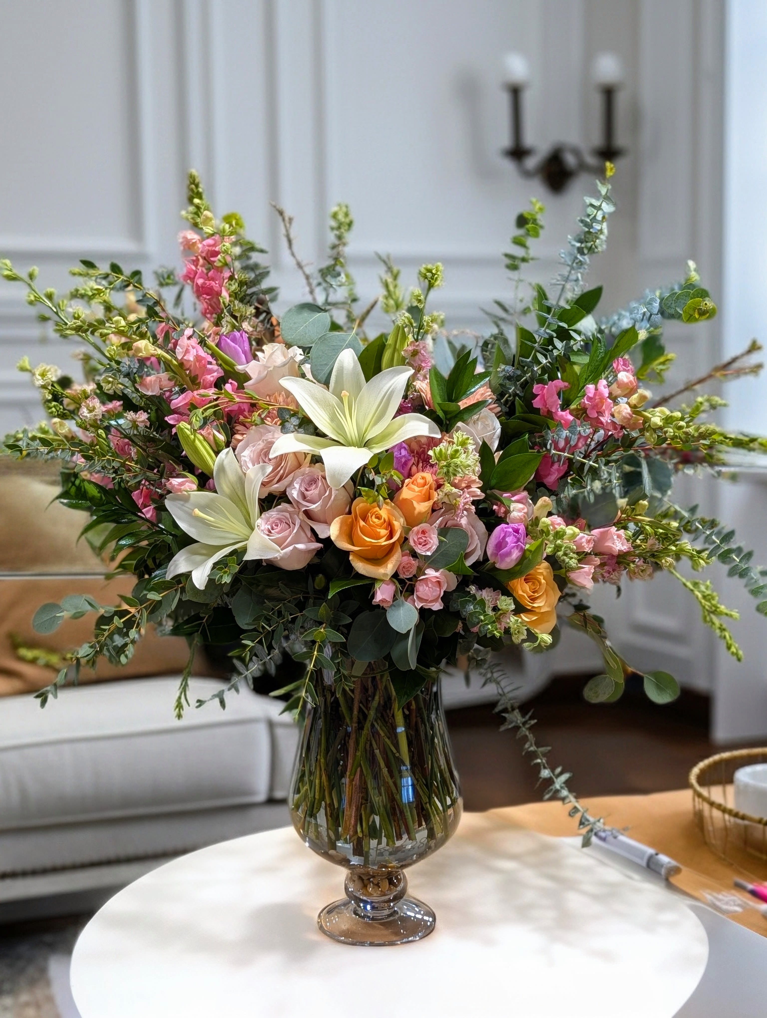Mixed bouquet of lilies, roses, and pink blooms in a glass vase