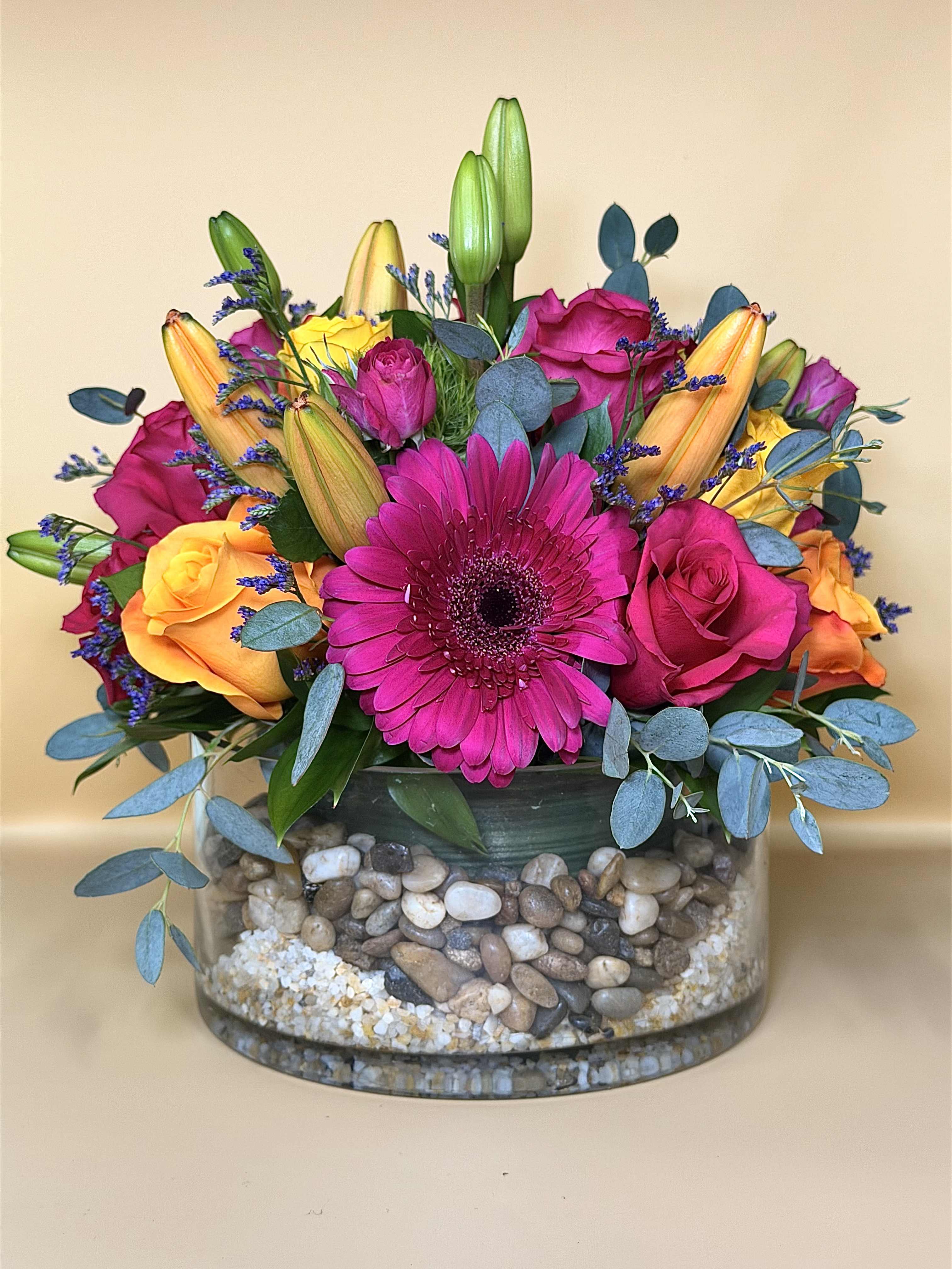 Bright mixed bouquet with pink gerbera, roses, and lilies in a glass vase