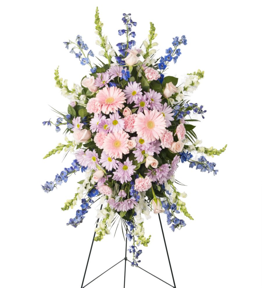 Standing floral spray with pink and lavender blooms on a black easel