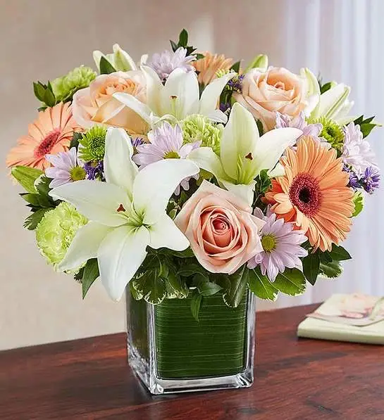 Healing Tears Multicolor Pastel - Soothe an aching heart with a sentimental tribute in soft, delicate shades. Our sympathy arrangement of pretty pastel roses, peach daisies, and white lilies, expertly gathered in a clear glass cube lined with a Ti leaf ribbon, makes for a warm gesture of comfort and healing.
