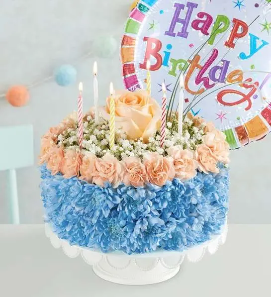 Birthday cake with flowers and candles, plus a colorful Happy Birthday balloon