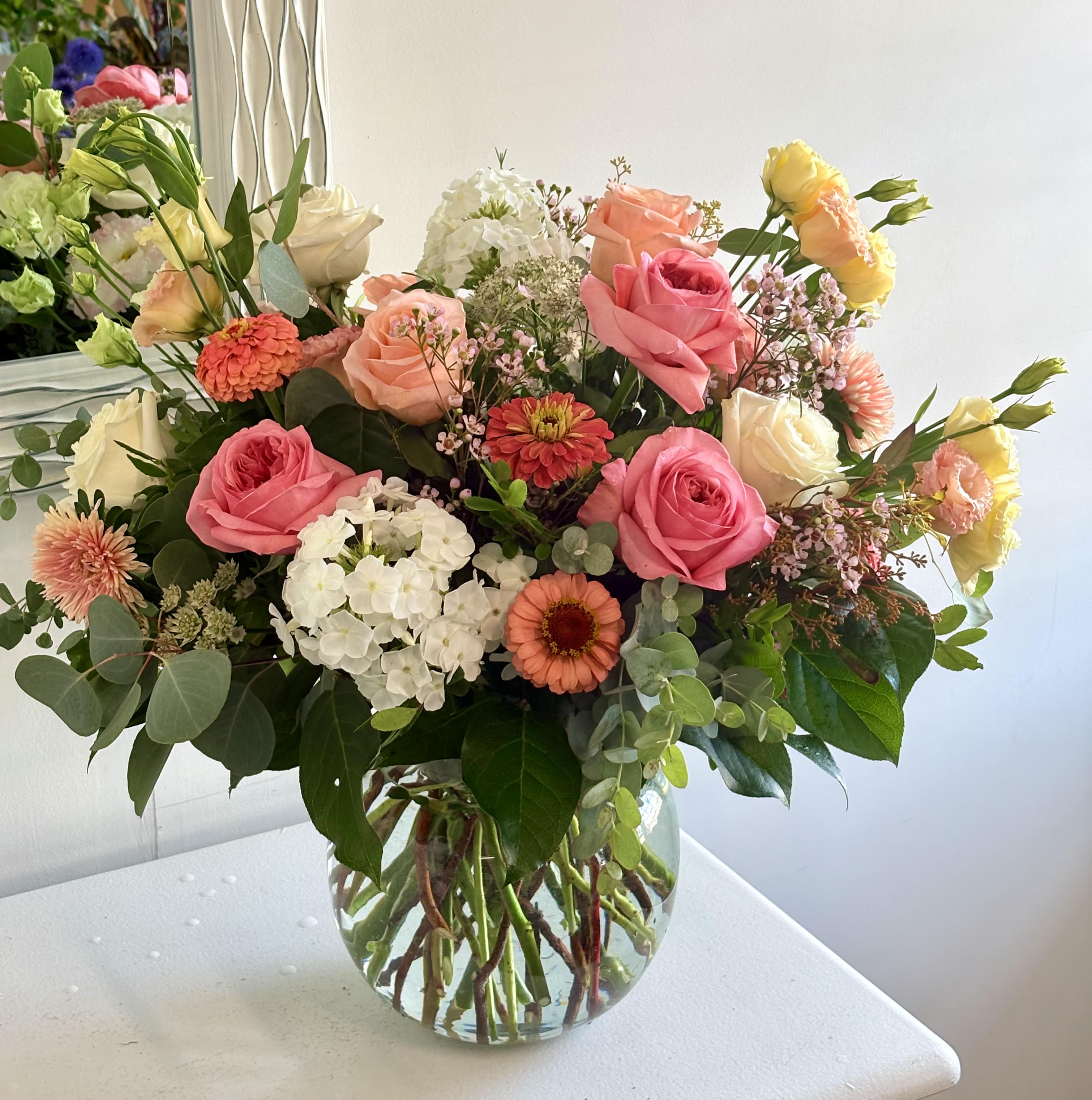 Mixed bouquet of pink and peach roses in a clear glass vase