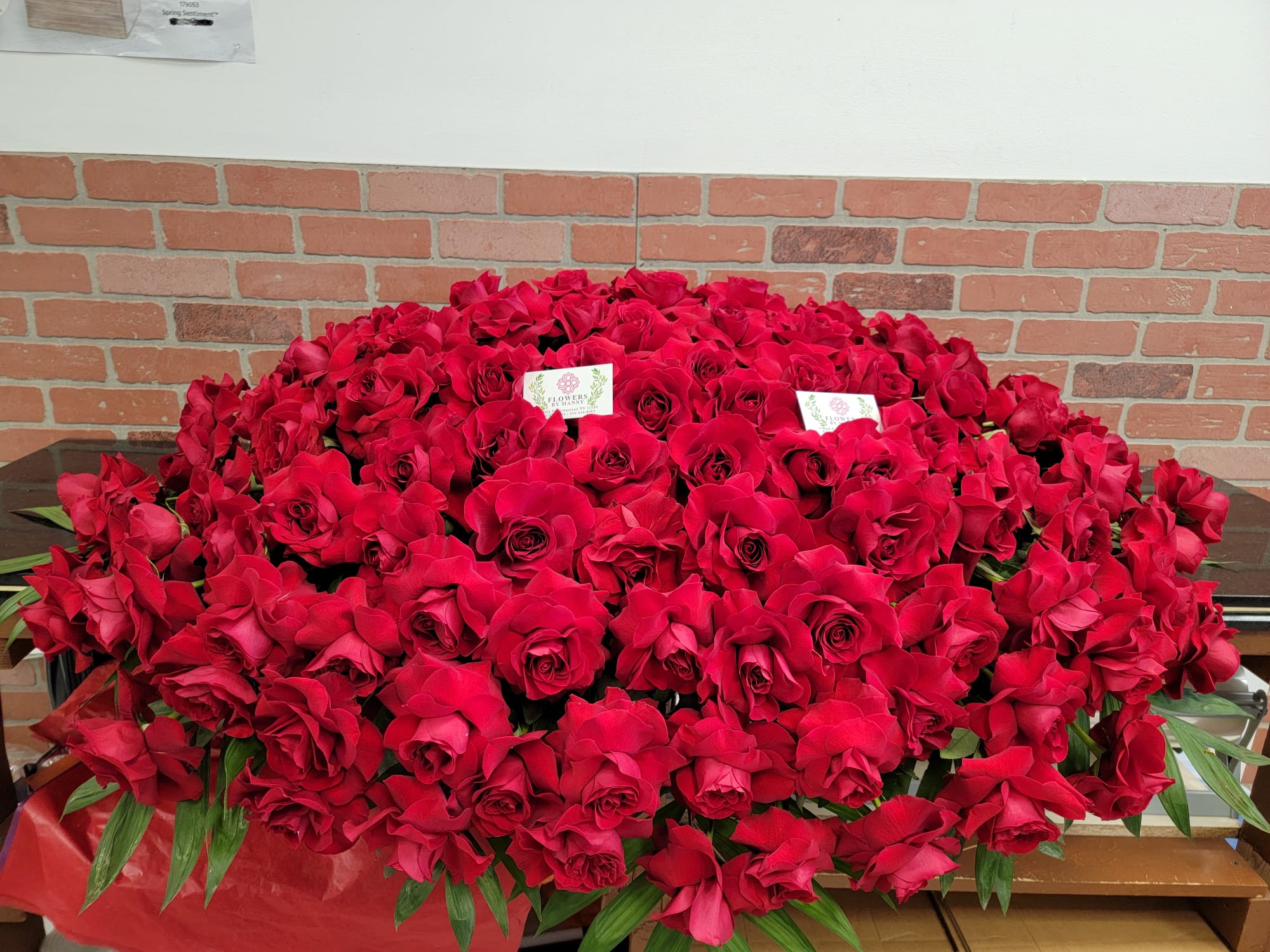 Large dome-shaped arrangement of red roses forming a dense casket spray.