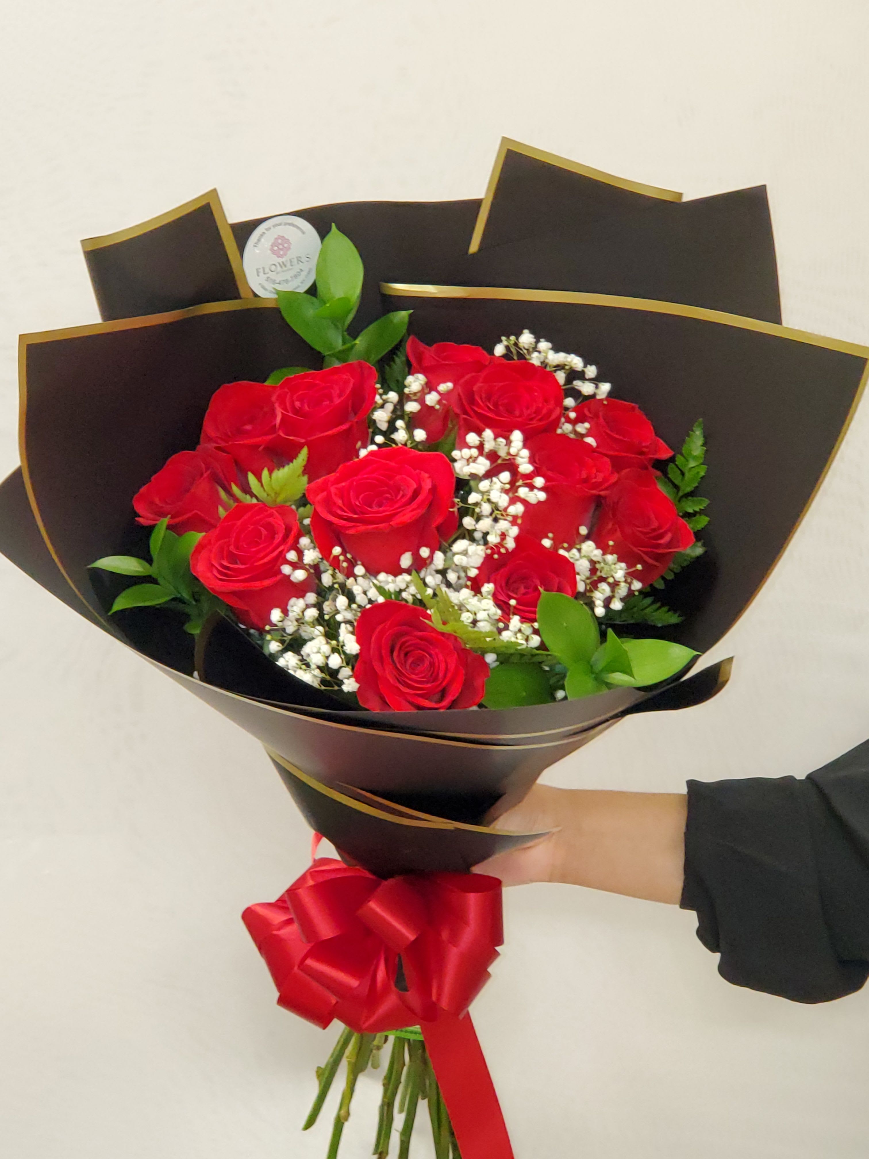 Bouquet of red roses with baby's breath in black wrap and a red ribbon