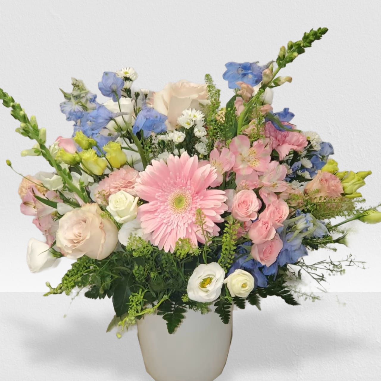 Pastel bouquet with pink gerbera, roses, and mixed blooms in a white vase