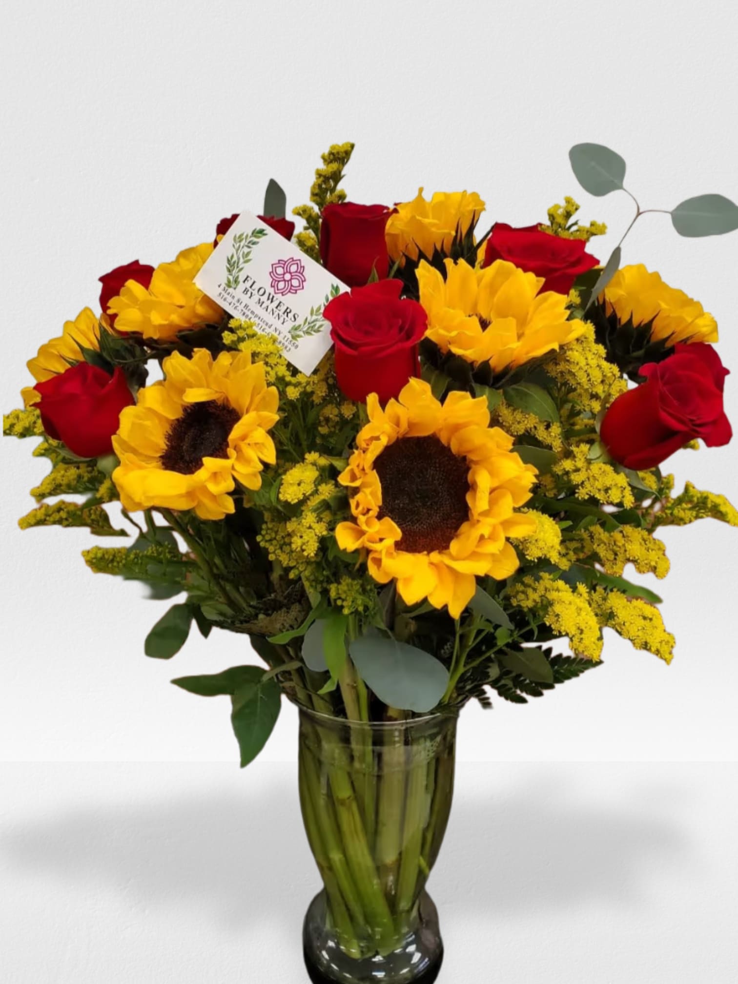Tall vase arrangement of yellow sunflowers and red roses with yellow filler flowers and a small card