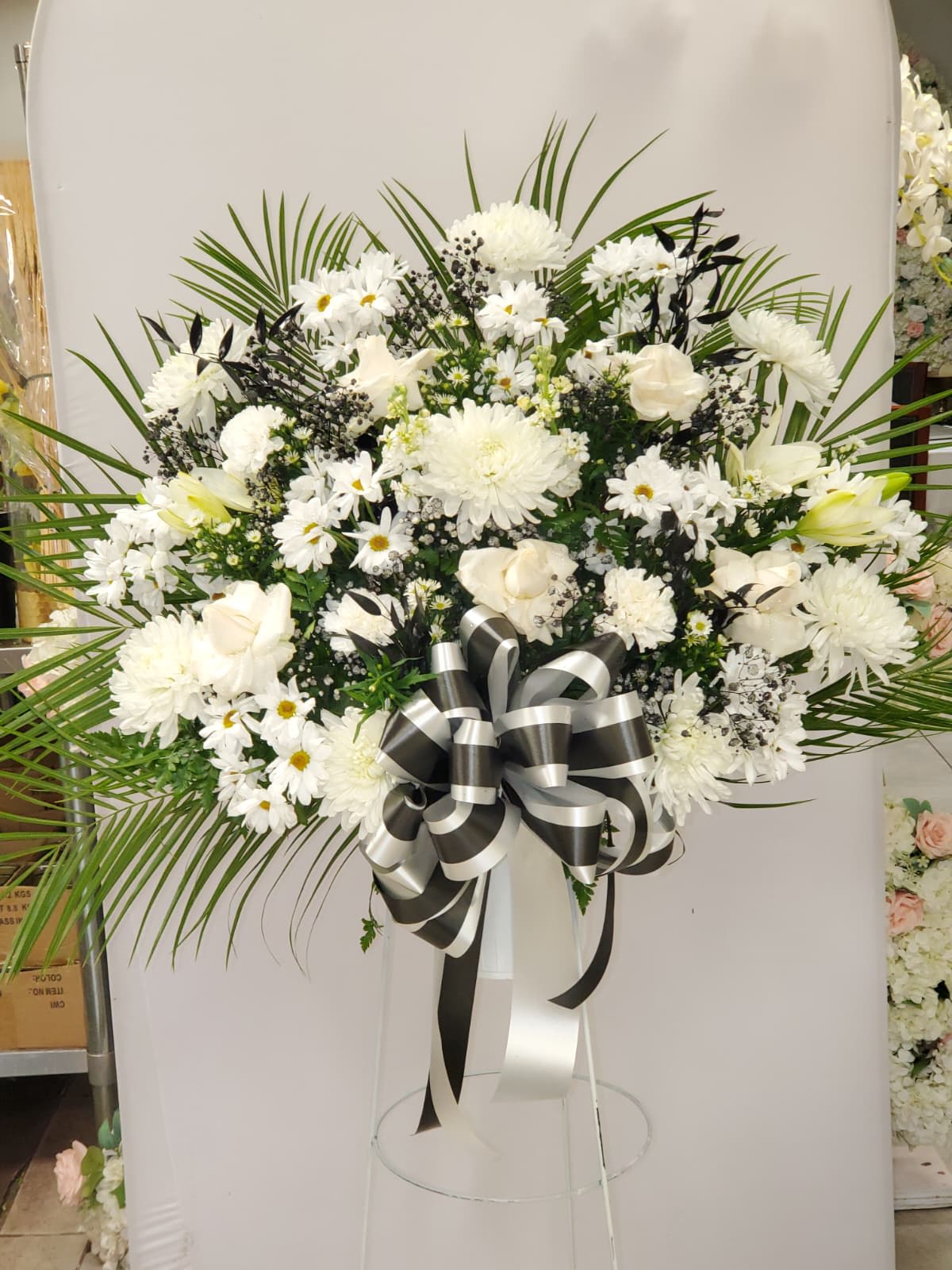 White funeral spray with daisies and chrysanthemums on a stand