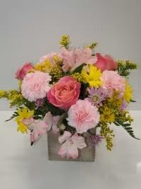 Pink and yellow mixed flower arrangement in a square vase