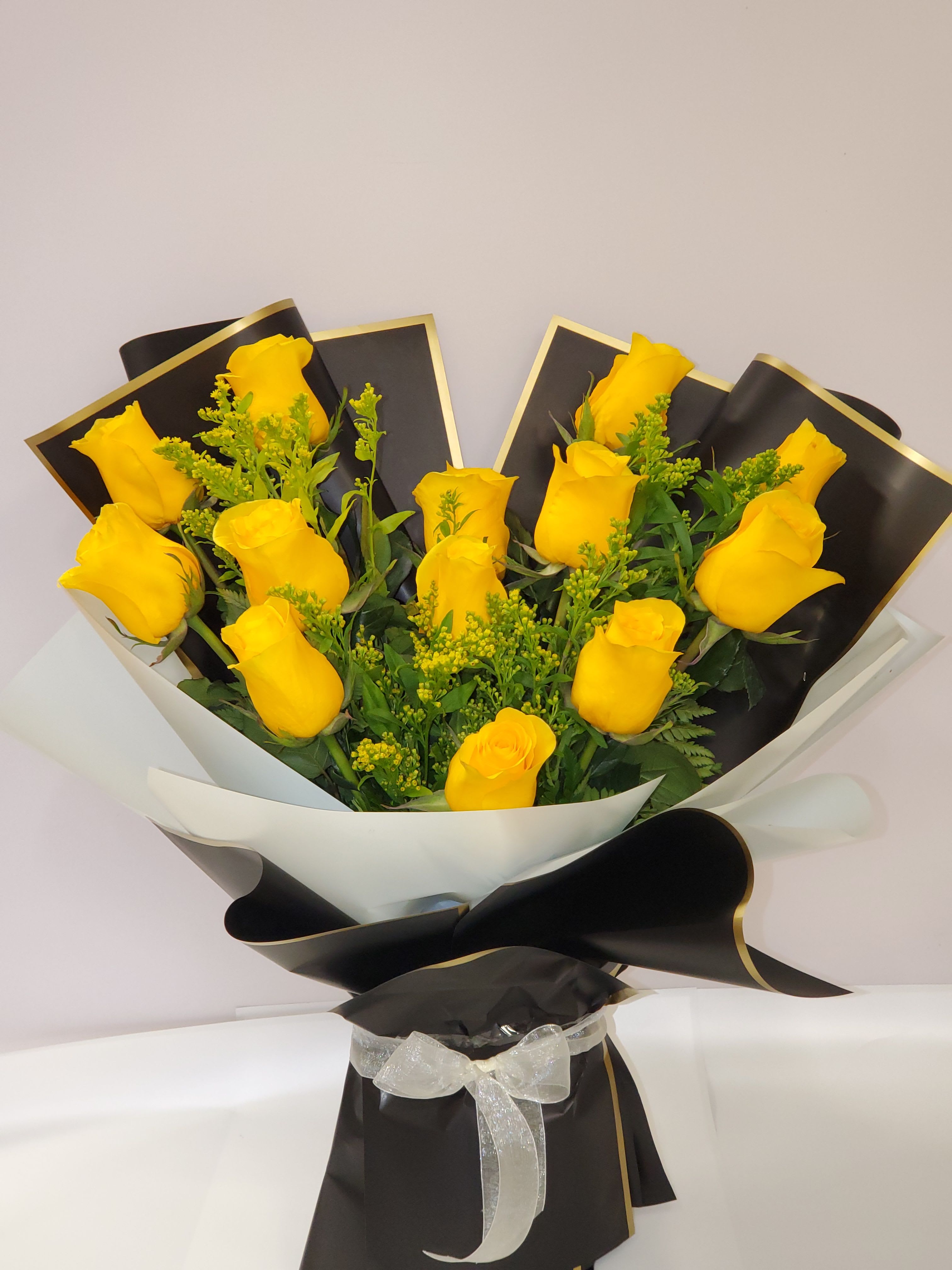 Bouquet of yellow roses wrapped in black and white paper