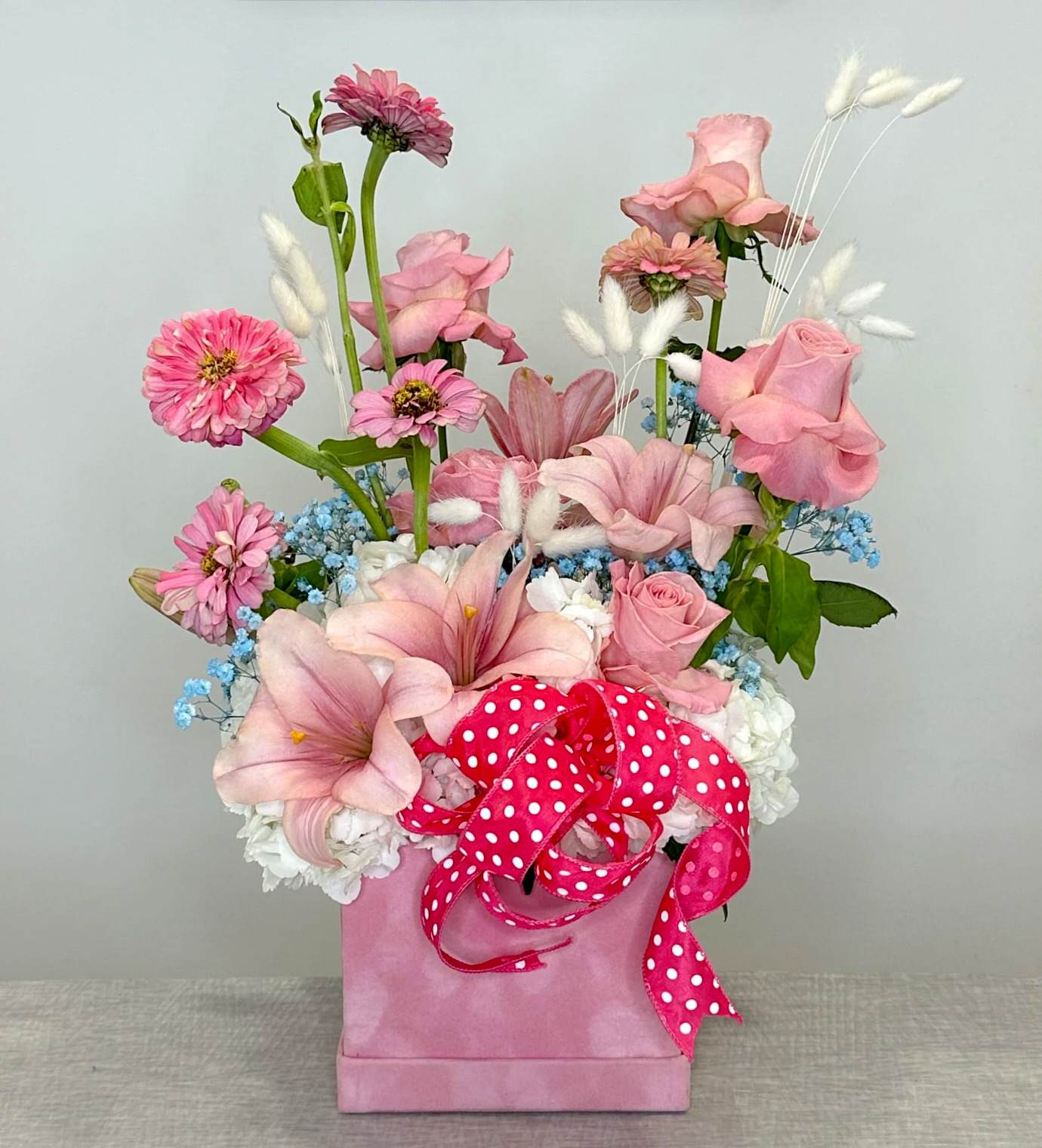 Pink floral arrangement in a pink box with a polka-dot ribbon