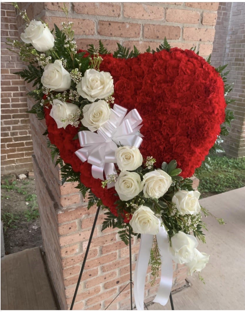 Heart-shaped red floral arrangement with white roses and a white bow