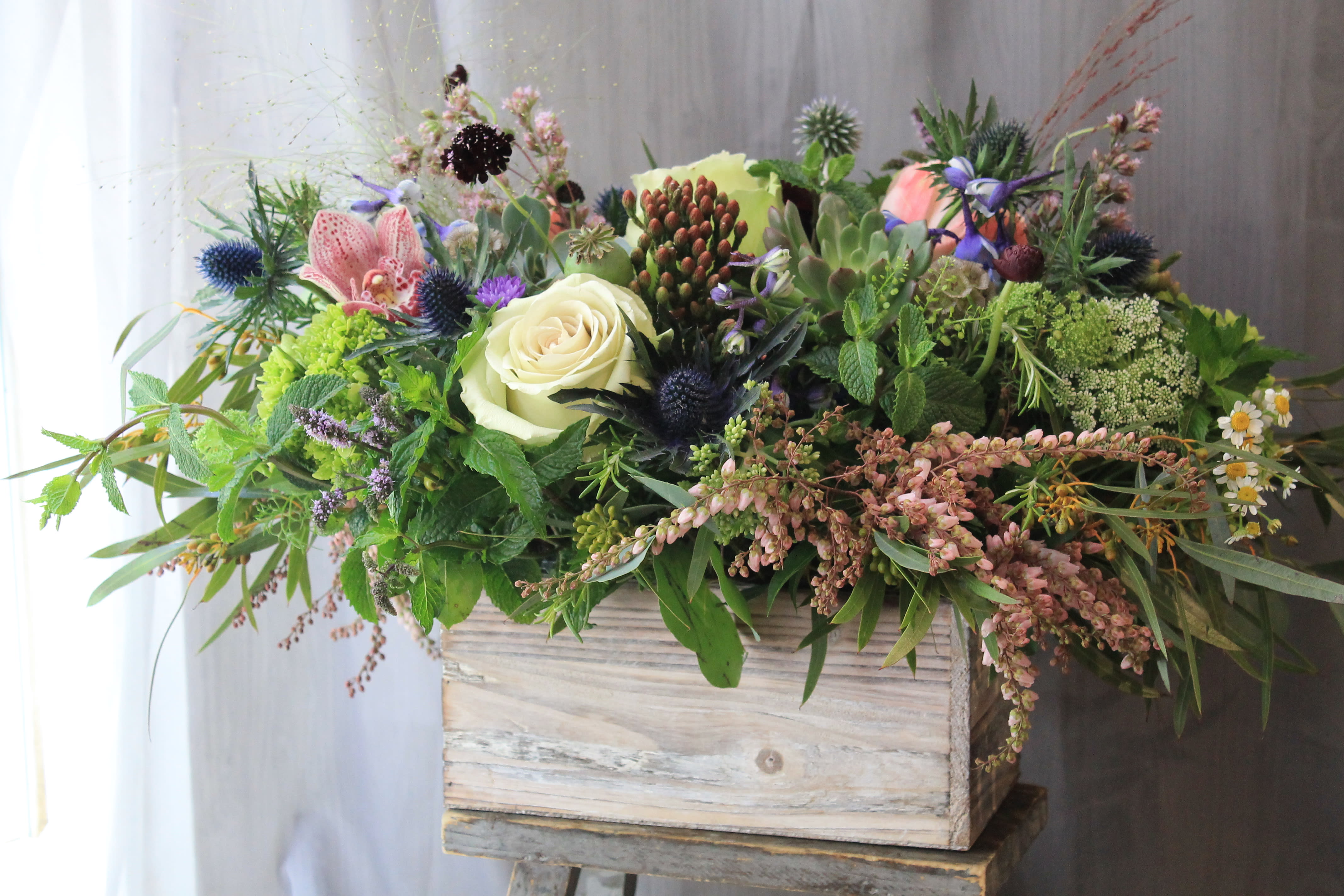 Mixed floral arrangement in a rustic wooden box with cream and pink blooms