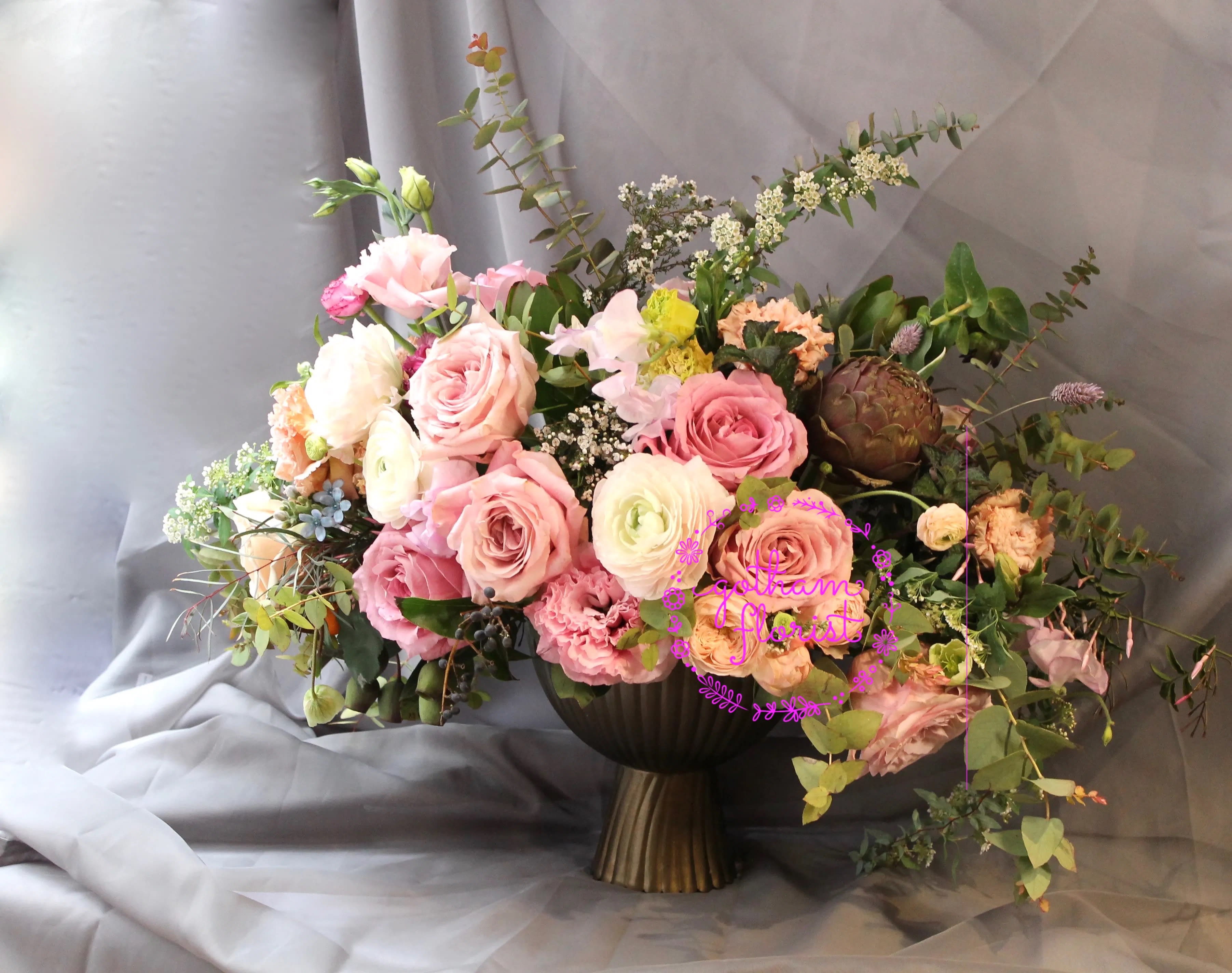 Large pastel bouquet of roses and mixed blooms in a dark vase