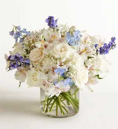 White and pale blue bouquet in a clear glass vase