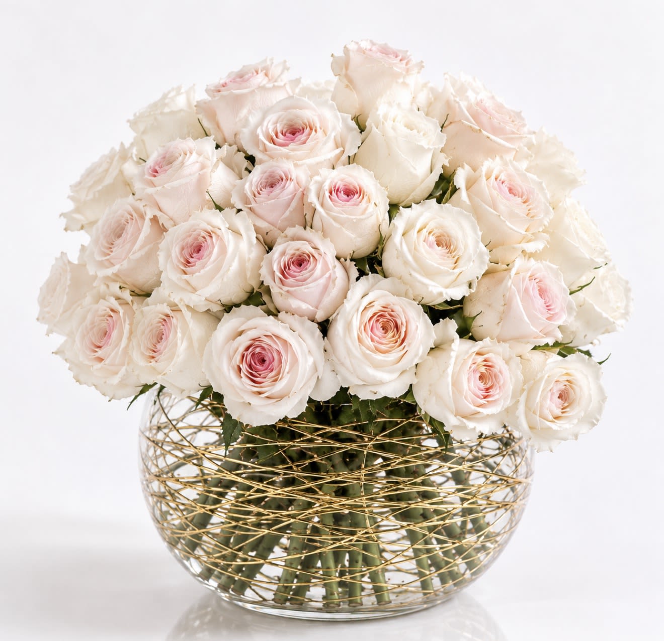 Gilded Blush - A luxurious gathering of premium blush and ivory roses artfully arranged in a signature glass bowl adorned with shimmering gold accents. Elegant, feminine, and unforgettable, Gilded Blush™ is designed to make a lasting impression for birthdays, anniversaries, celebrations, and life’s most meaningful moments