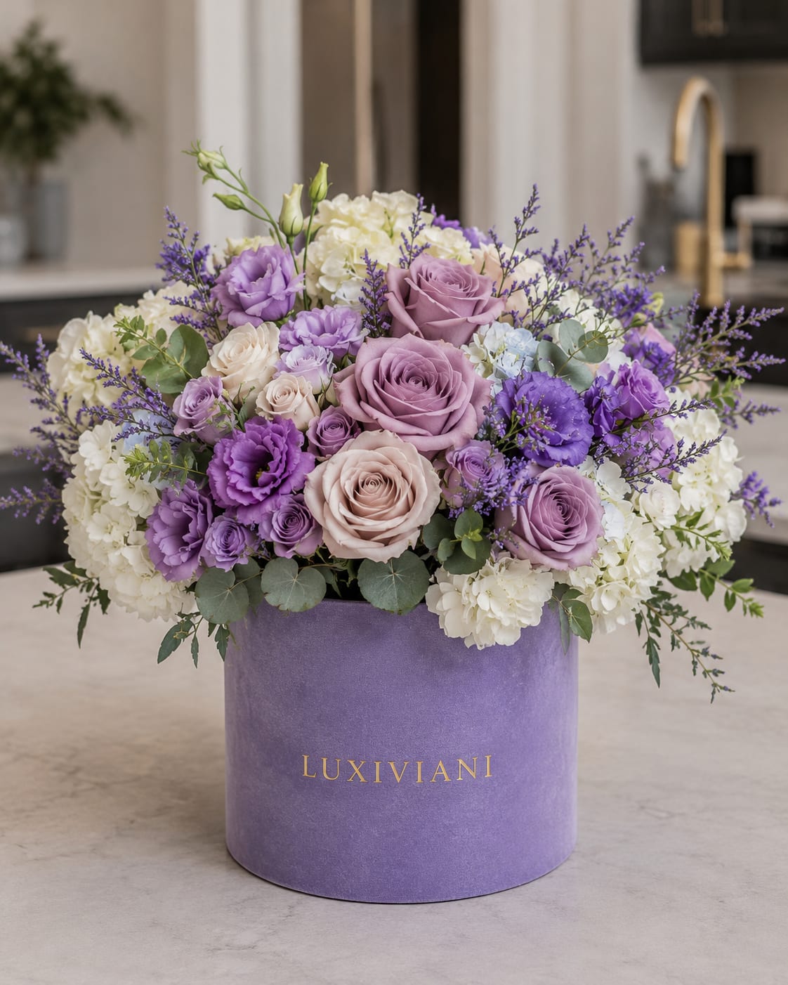 Lavender Reverie - Lavender, blush, and white roses arranged with white hydrangeas and purple lisianthus create a soft, romantic birthday bouquet or anniversary gift that reads like a whisper of spring. The rounded hat box presentation gives this floral arrangement a refined, gift-ready look-perfect for weddings, anniversaries, or to let someone know you're thinking of them in a graceful, memorable way.  The composition sits low and wide in a lavender hat box, mixing lush hydrangea heads with velvety roses and delicate lisianthus. Fine purple filler blooms and trailing eucalyptus add airy texture and a subtle green contrast that brightens the pastel palette. Colors include purple, white, pink, and green for an elegant, calming effect that complements both modern and classic décor.  This arrangement is meant to make the recipient feel truly seen and celebrated-ideal for a close friend, partner, or mother on a special day. The hat box keeps the design compact and display-ready; water and care instructions are included so the bouquet can be enjoyed for days after arrival.