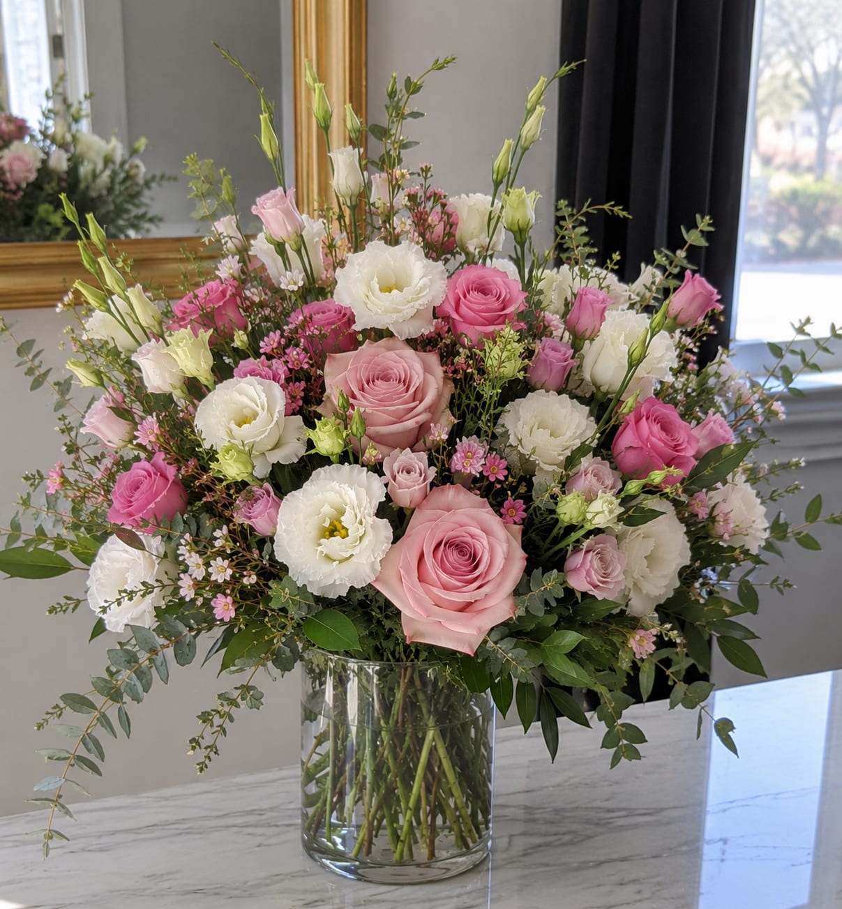 Pink and white roses with white lisianthus in a glass vase