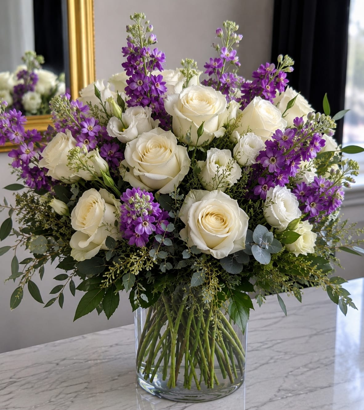 White roses and purple flowers in a clear glass vase