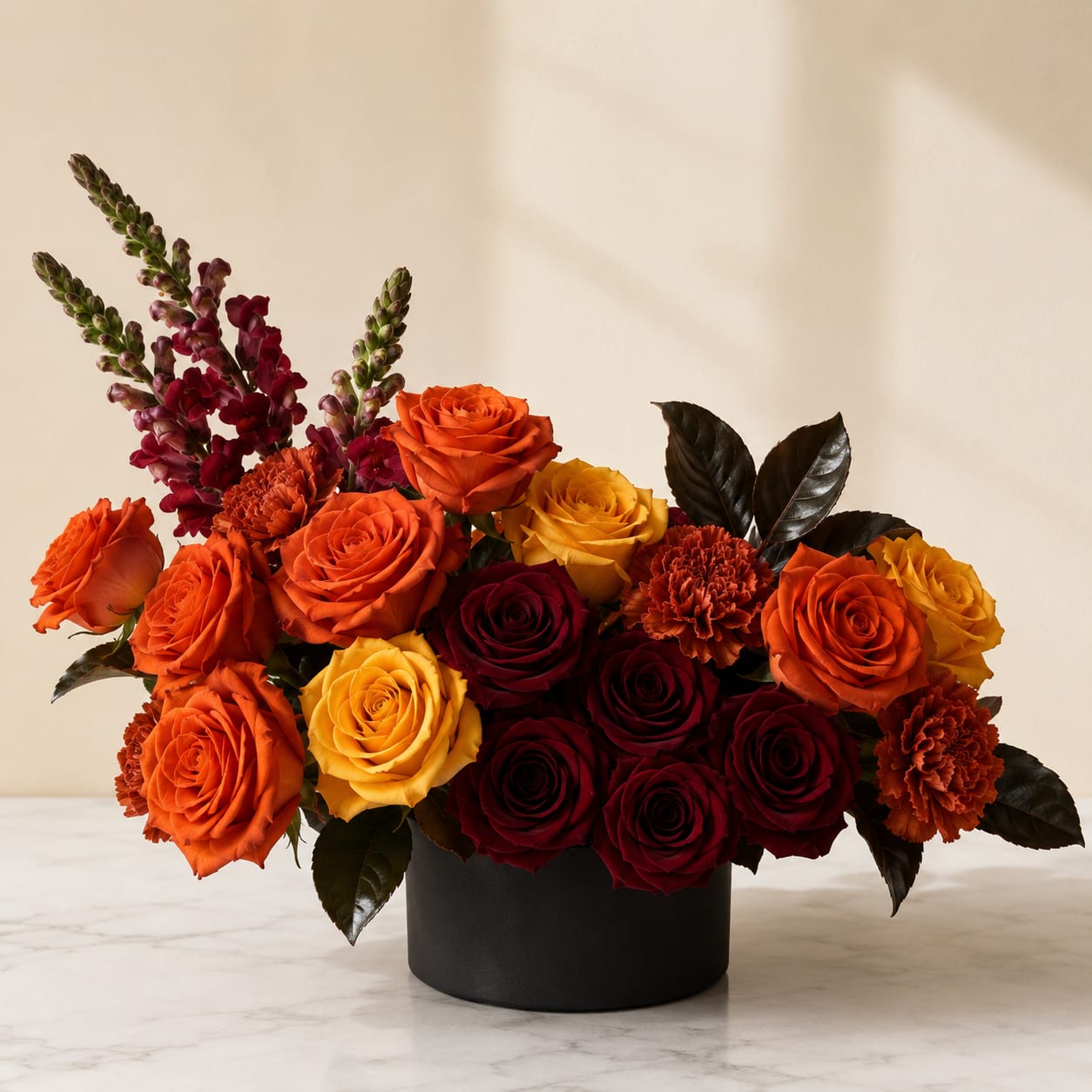 Arrangement of orange, yellow, and burgundy roses in a black vase