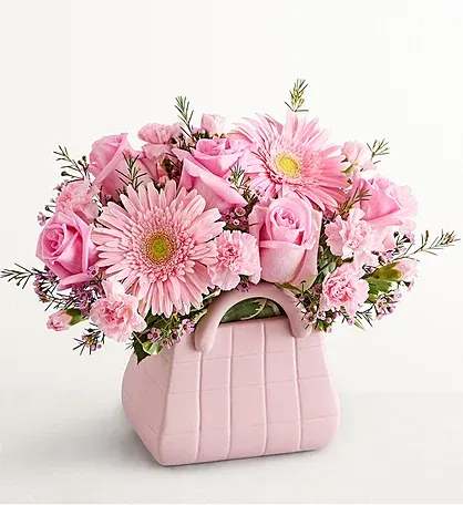  Blush Garden Handbag - A soft and elegant expression of spring, the Blush Garden Handbag features a curated blend of blush-toned blooms artfully arranged in a signature handbag vase. Designed with a lush focal garden rose, delicate tulips, and full hydrangea, this piece offers a refined, romantic look with a modern edge.    Thoughtfully styled for effortless beauty, this arrangement is perfect for birthdays, celebrations, or simply elevating everyday moments with a touch of luxury.  