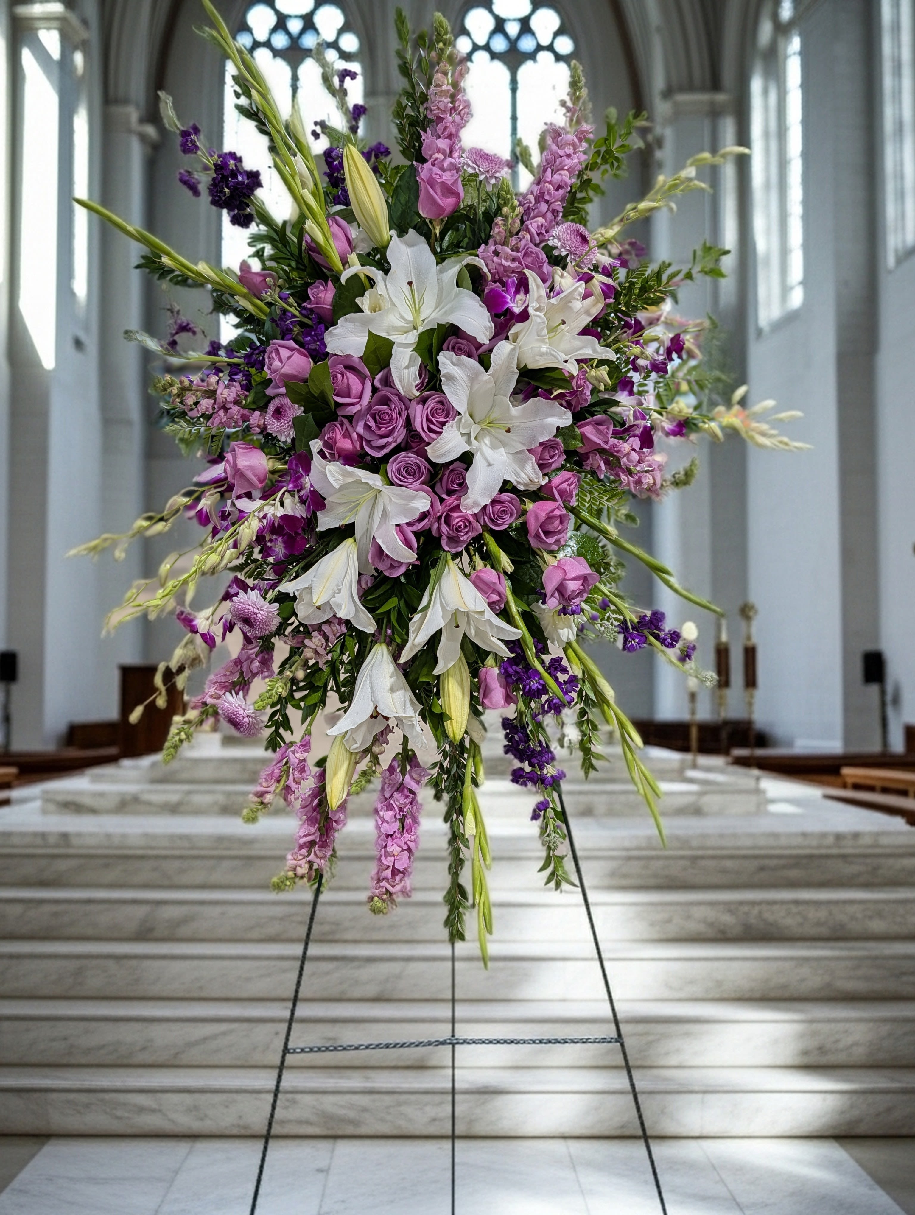 Large purple and white floral standing arrangement on an easel