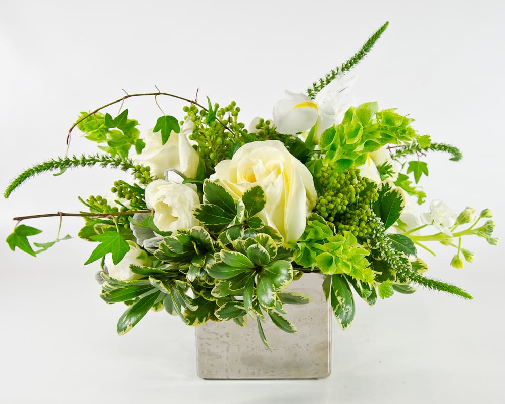 White roses and green flowers in a square glass vase