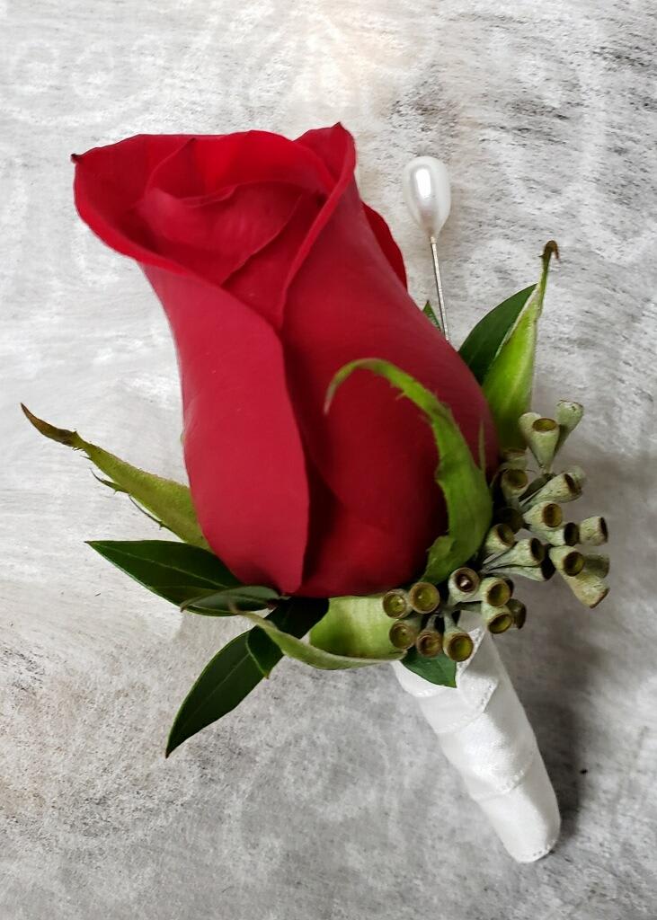 Single red rose boutonniere with green accents and white ribbon wrap