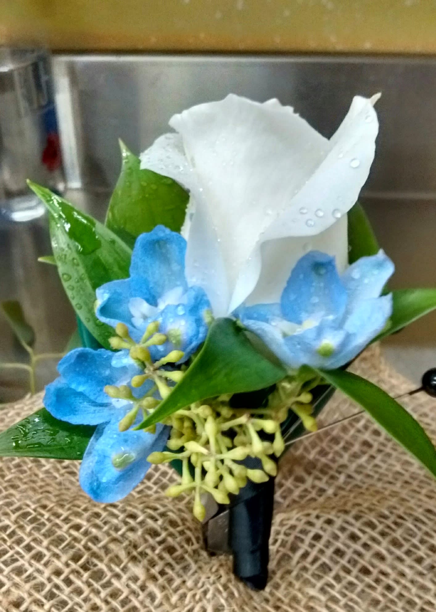 White calla lily with blue flowers in a small boutonniere