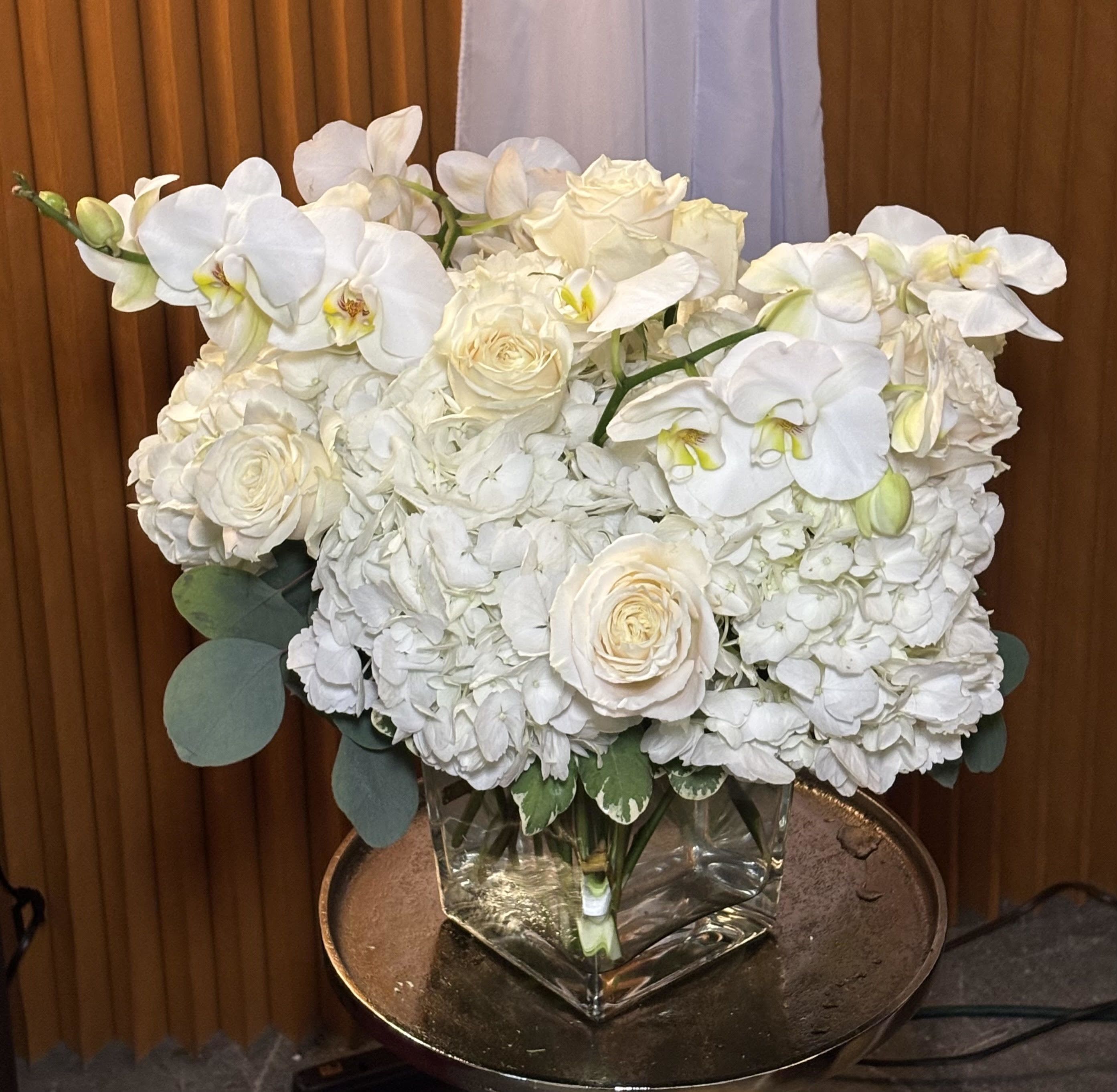 White orchids and roses arranged in a square glass vase