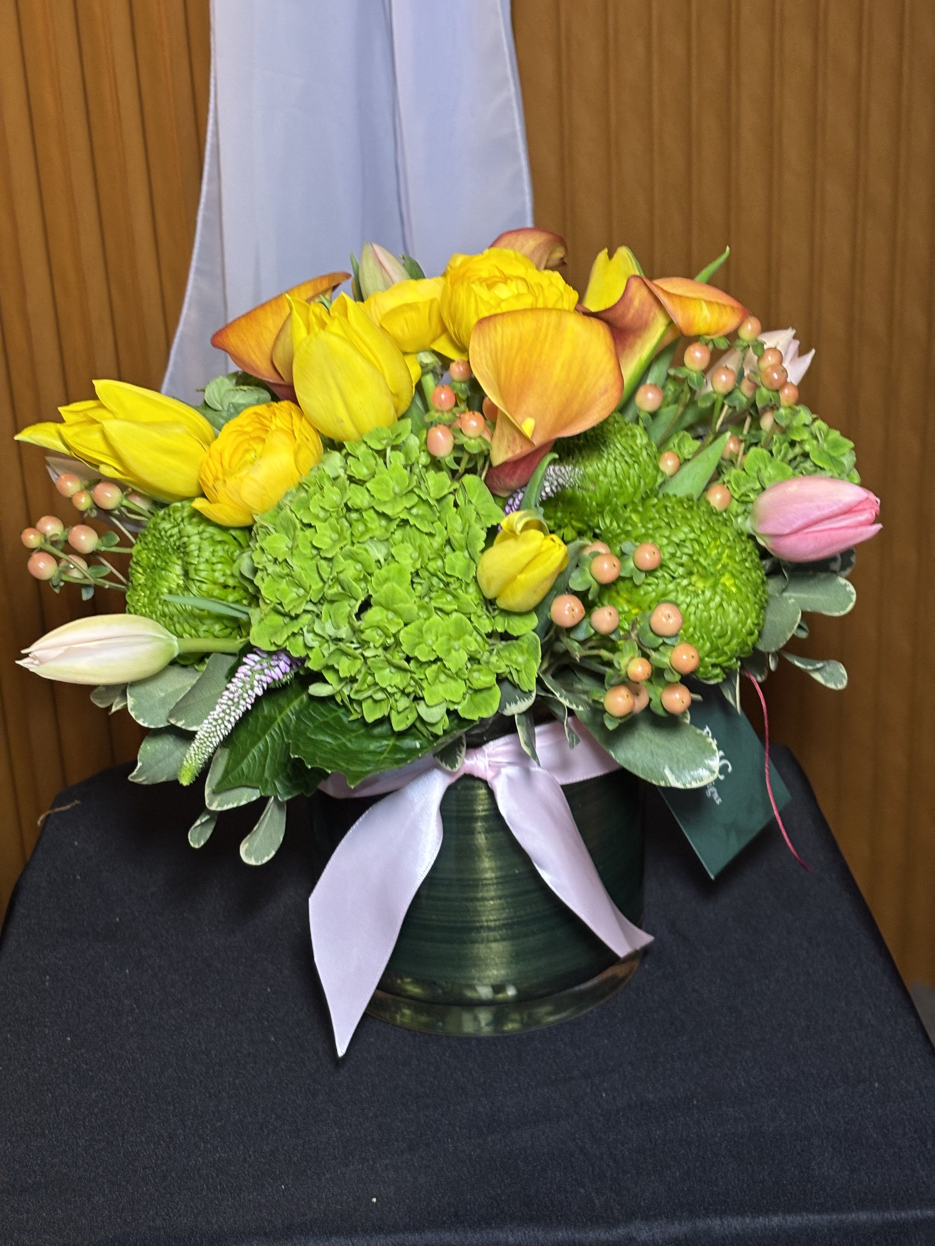 Bouquet of yellow tulips, green hydrangea, and orange calla lilies in a vase