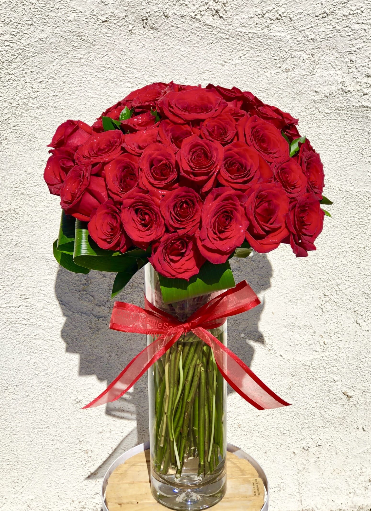 Bouquet of red roses in a clear glass vase with a red ribbon