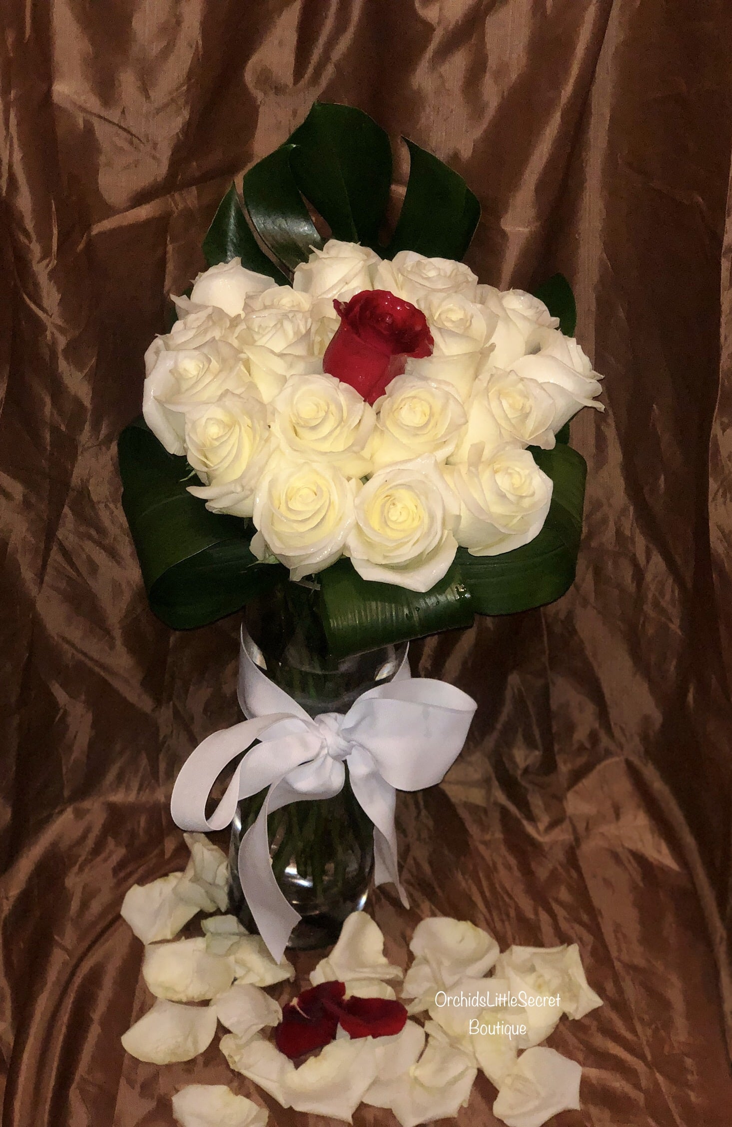 Bouquet of white roses with one red rose in a glass vase