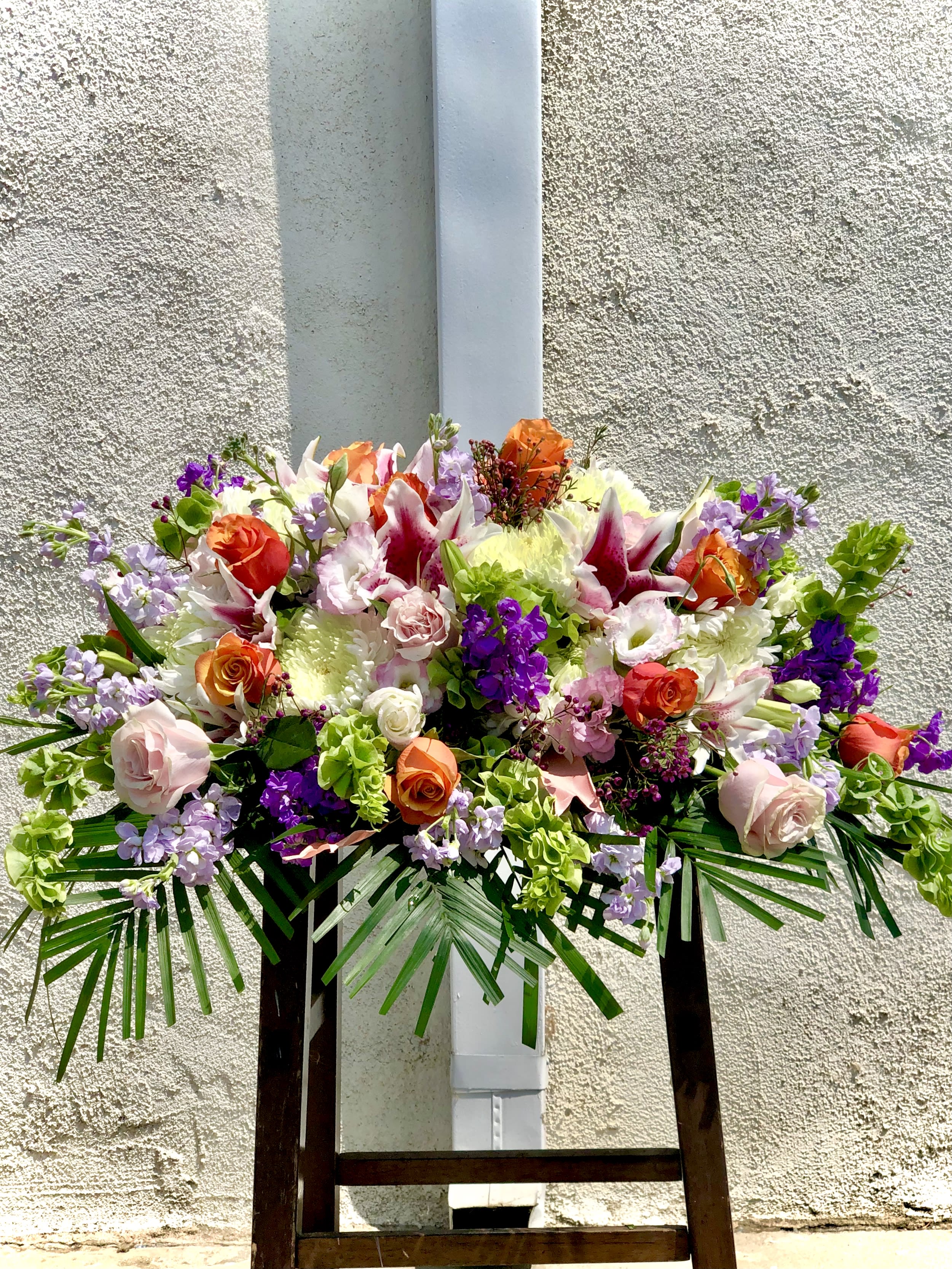 Large mixed floral arrangement with roses, lilies, and purple accents