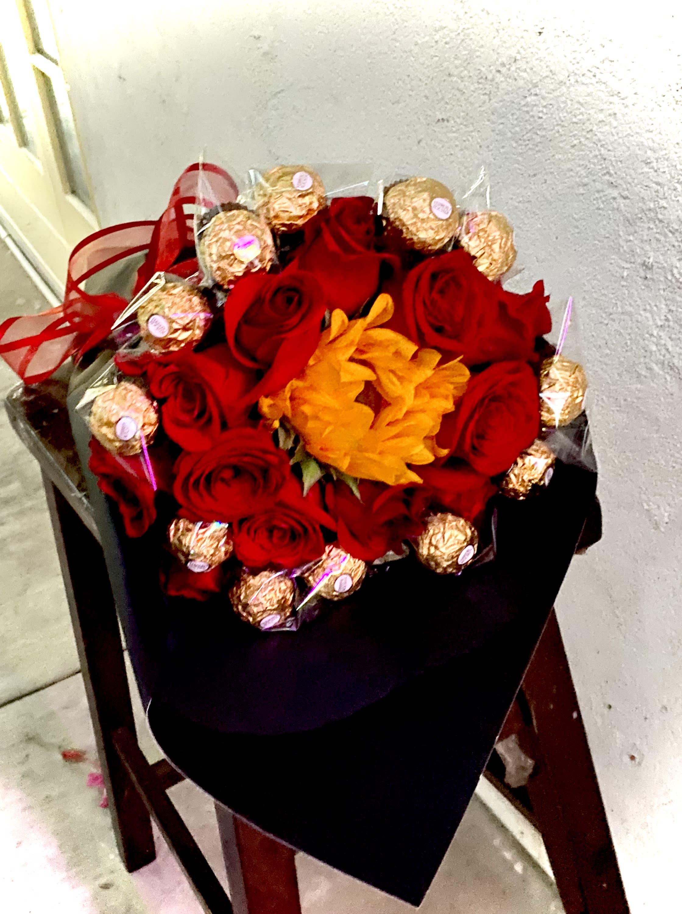 Bouquet of red roses with gold-wrapped chocolates and an orange flower