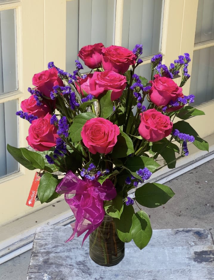 Bouquet of hot pink roses with purple filler in a glass vase