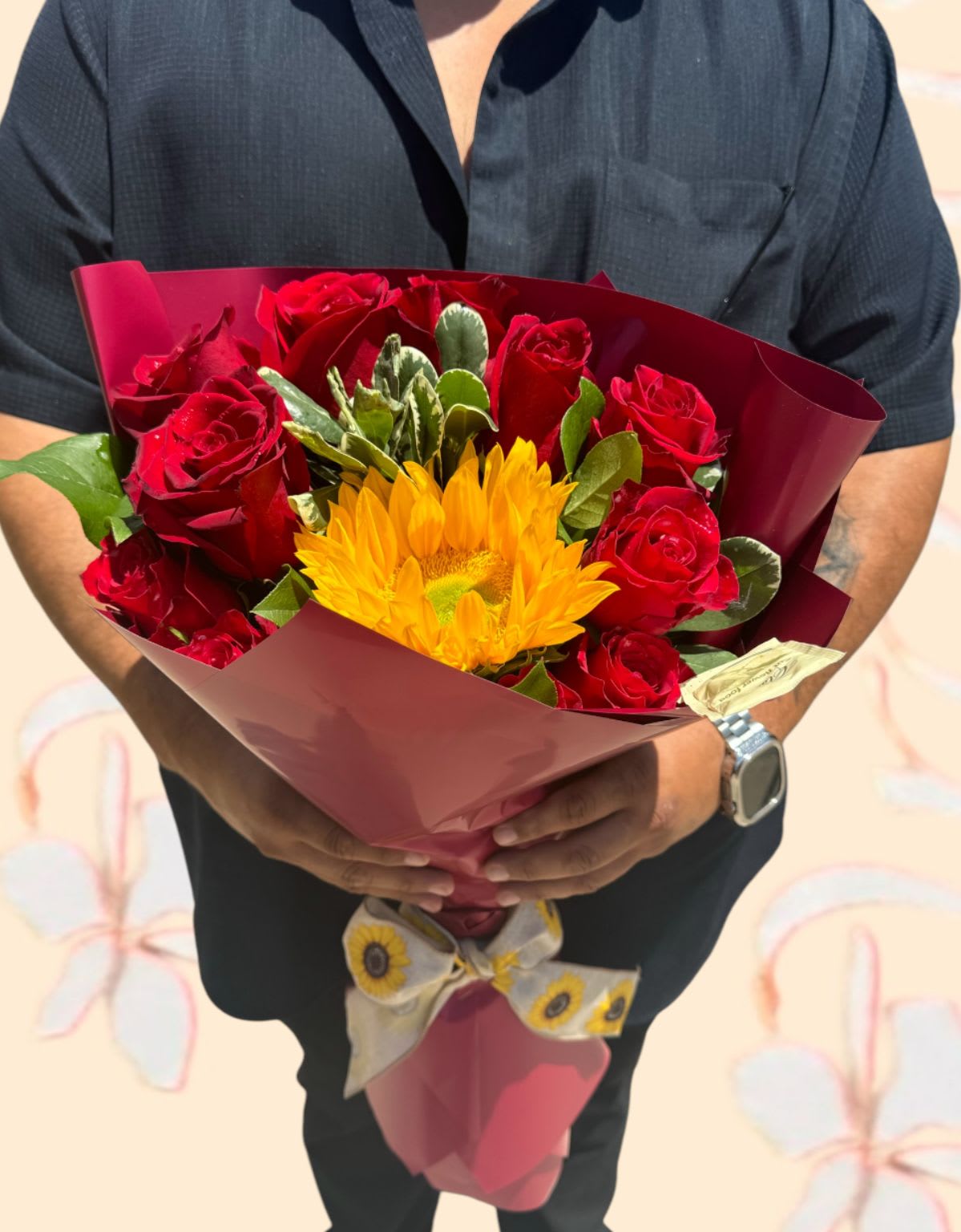 Bouquet of red roses and a yellow sunflower wrapped in burgundy paper