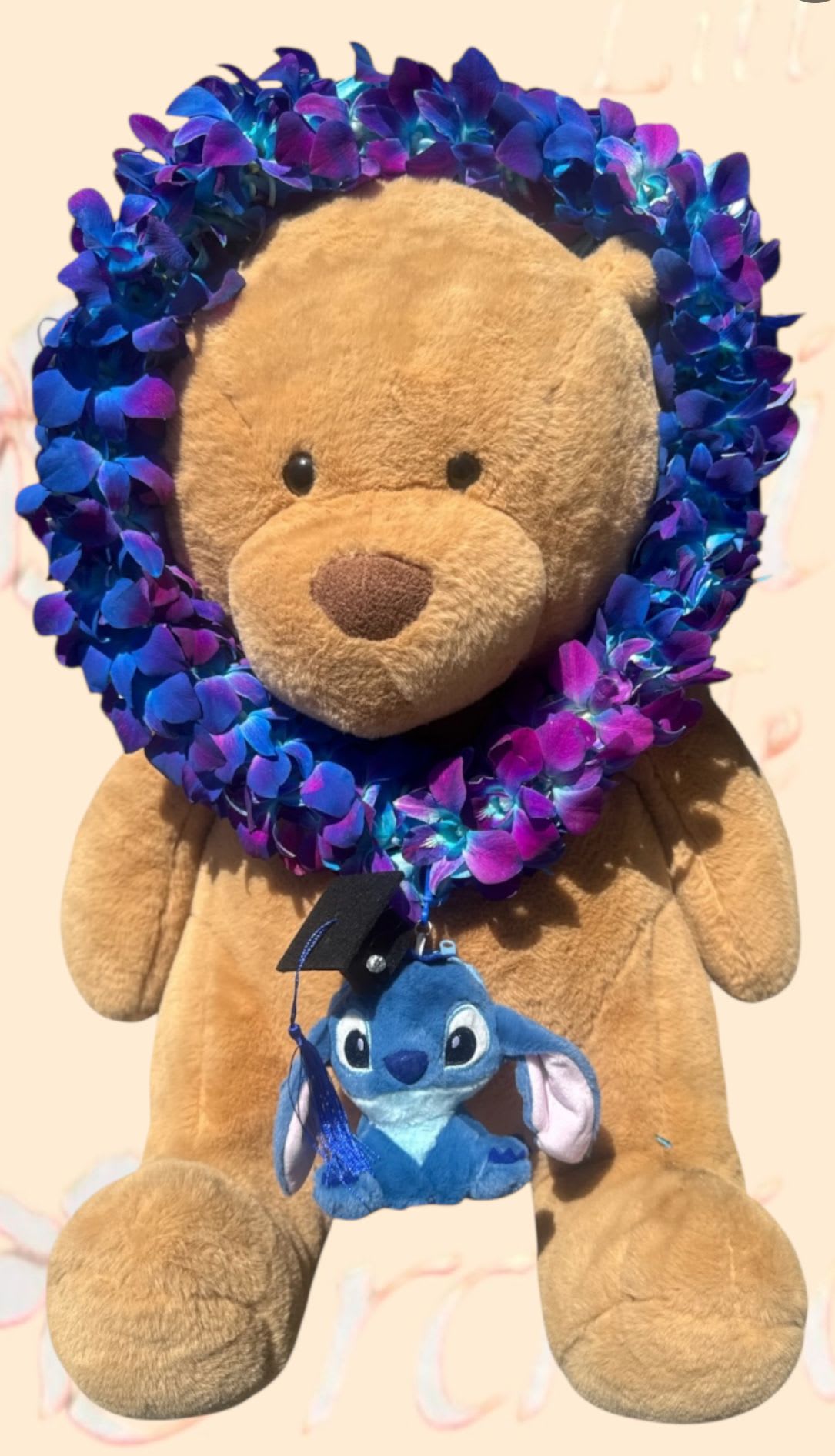 Teddy bear with a blue-purple flower lei and a small plush character hanging from it
