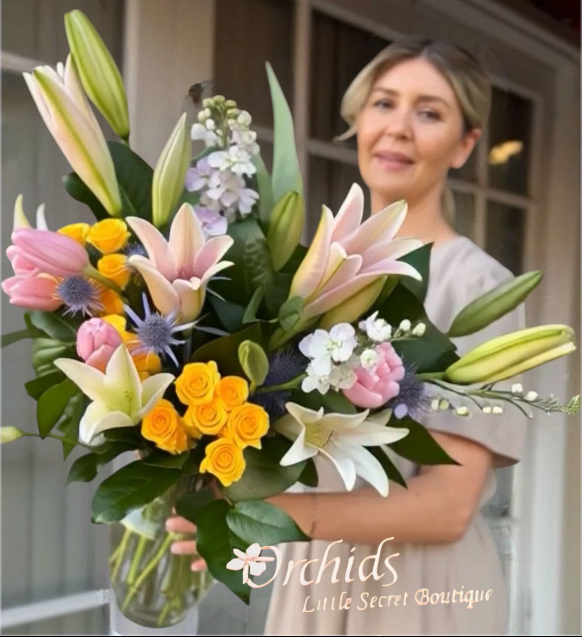Large bouquet of lilies, roses, and small white flowers in a glass vase