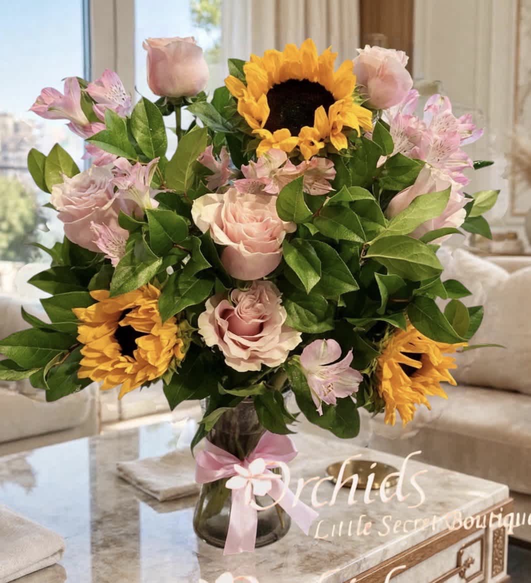 Bouquet of pink roses, sunflowers, and alstroemeria in a glass vase