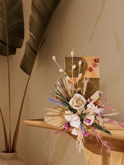 Dried floral arrangement with cream roses and pink accents on a wooden shelf