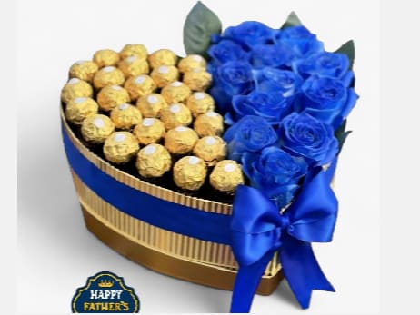 Blue Treasure for Dad - Celebrate Father's Day with a modern and elegant combination. Premium heart-shaped box artistically divided between superior quality blue roses and a delicious selection of gourmet chocolate bonbons.