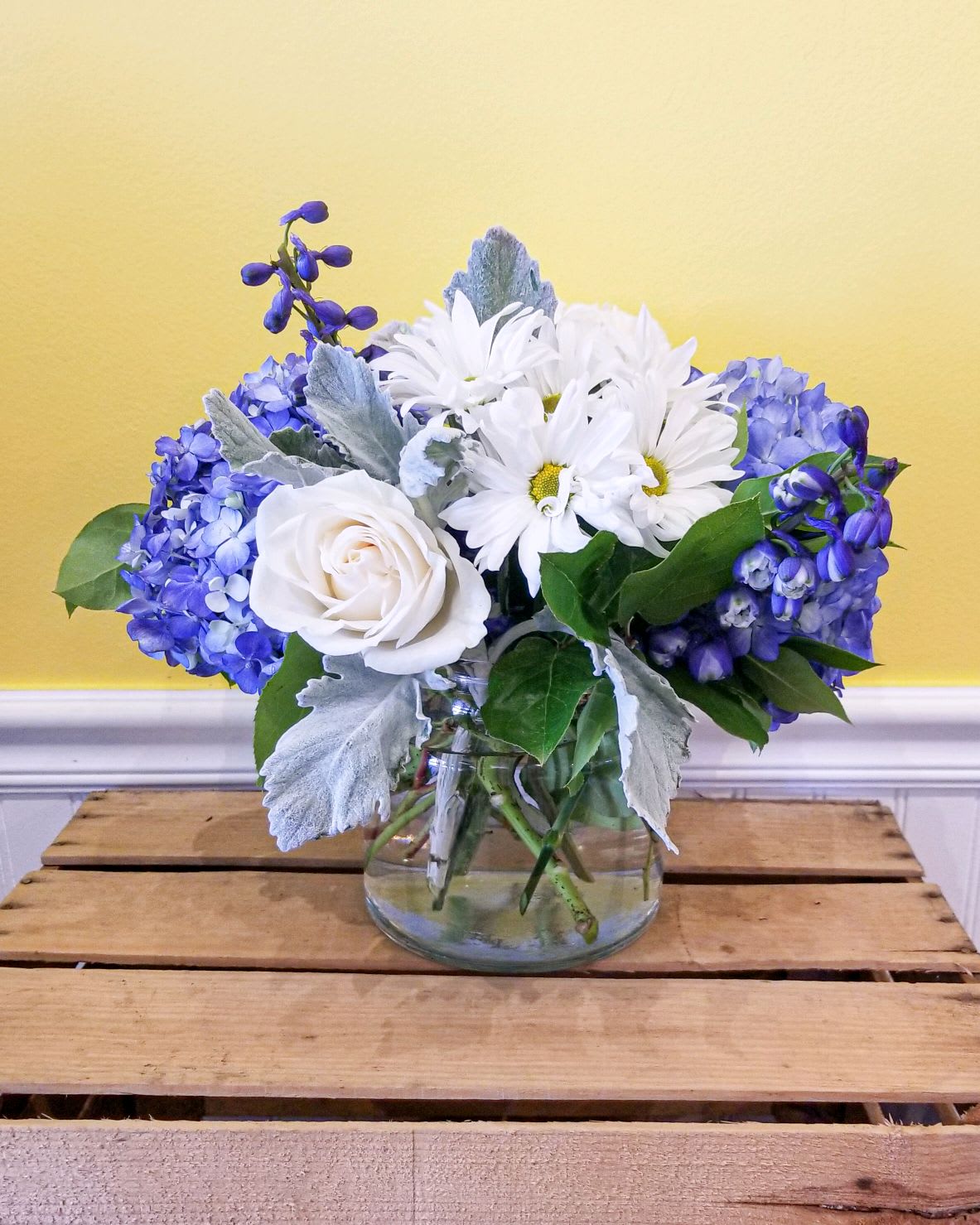 Blue and white flowers arranged in a clear glass vase