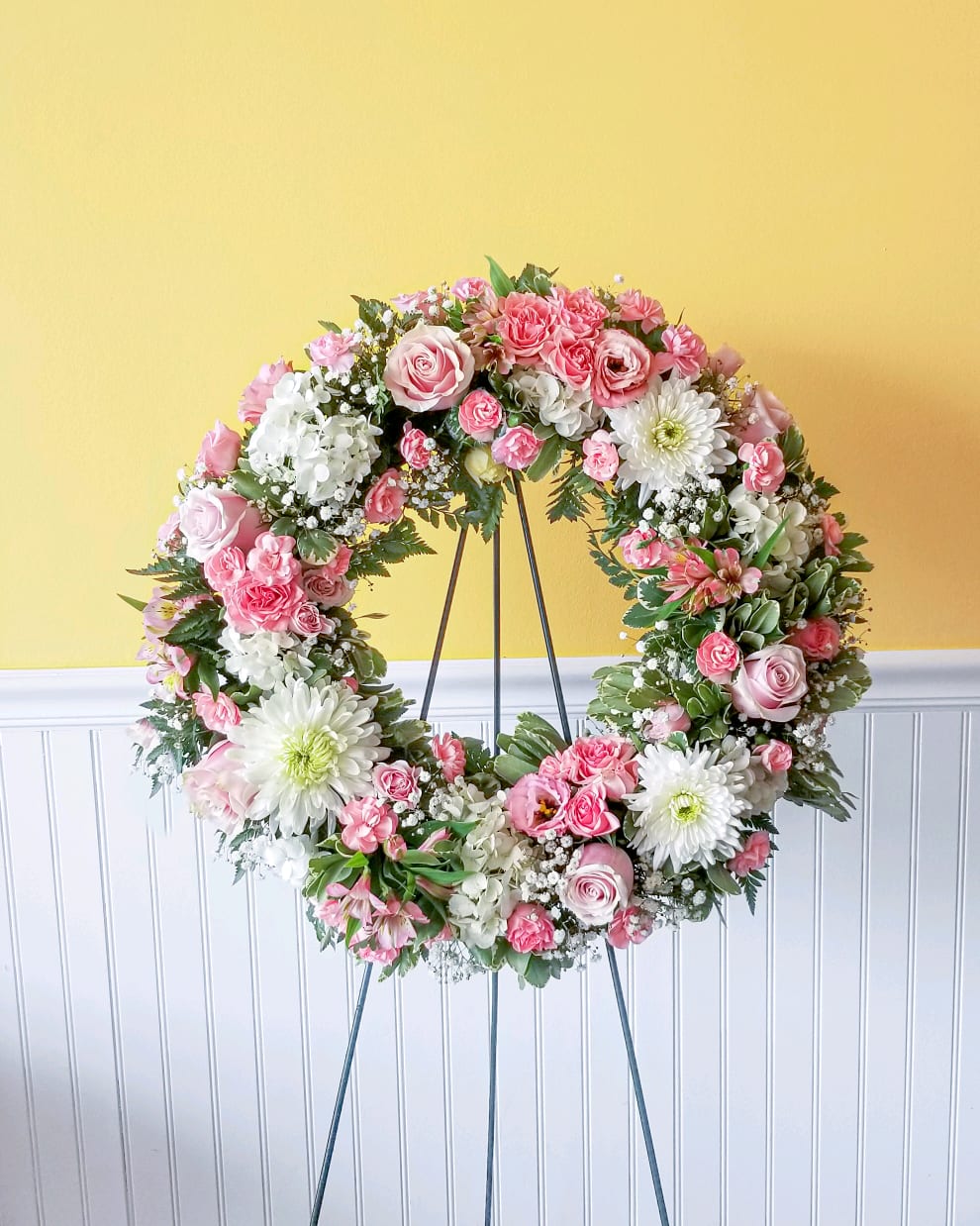Pink and white floral wreath on a metal stand