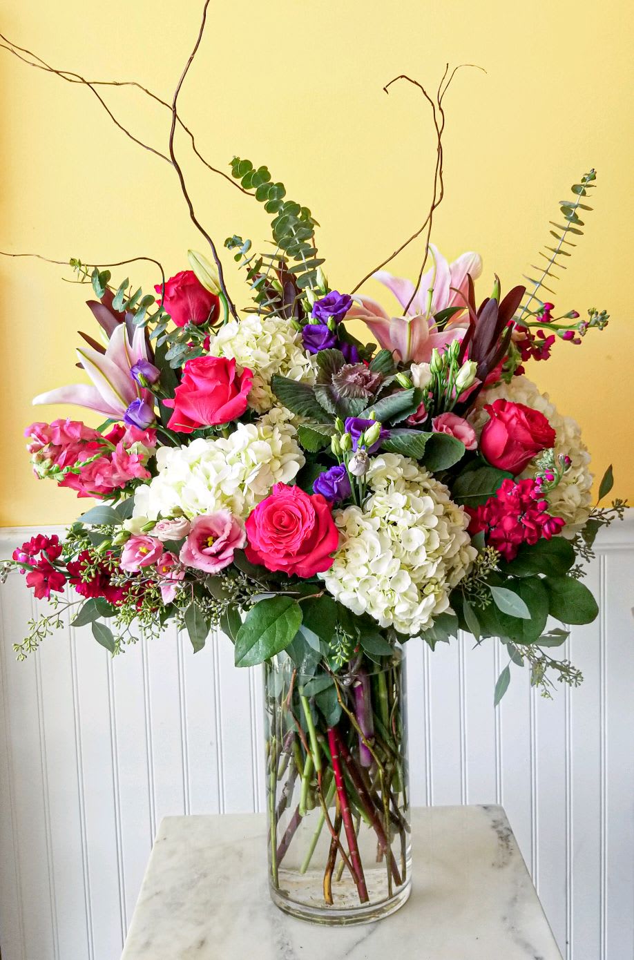 Large mixed bouquet of pink, white, and purple flowers in a glass vase