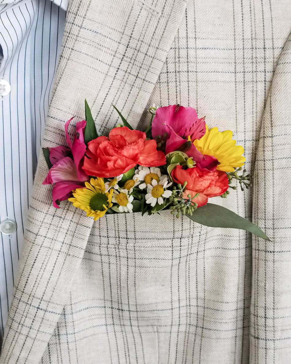 Small bouquet of pink, red, and yellow flowers pinned to a plaid jacket