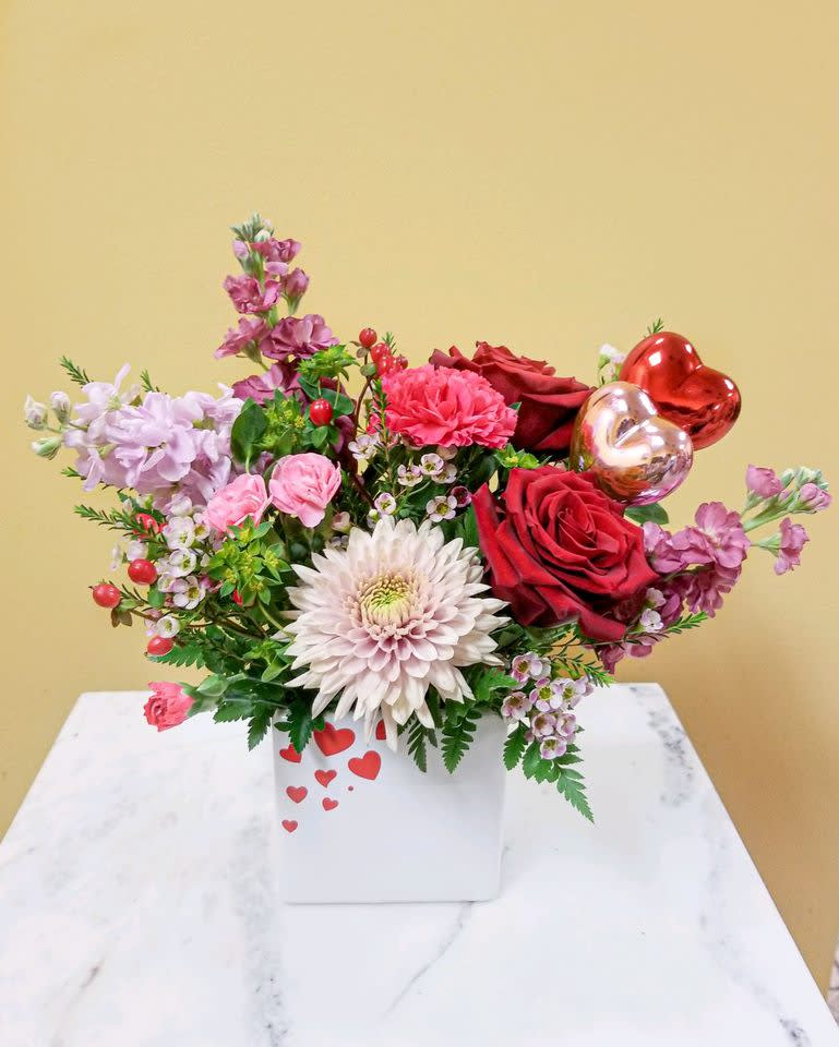 Mixed bouquet with red roses, pink blooms, and heart balloons in a white box